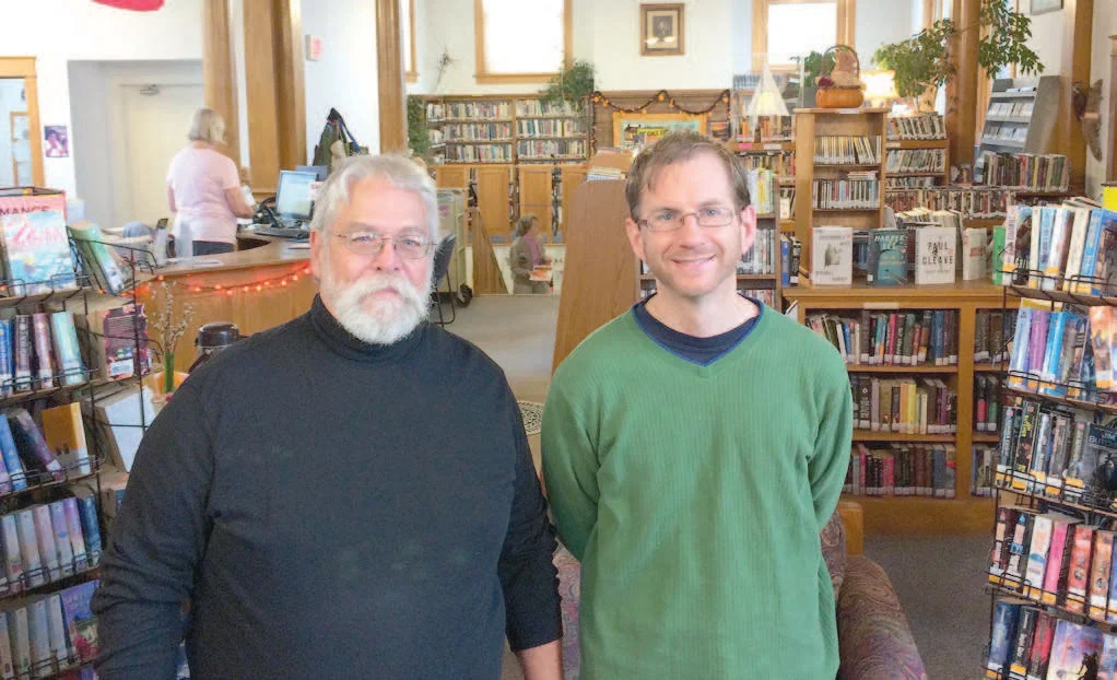 Don Albrecht (left), president of the Bayfield Carnegie Library board, and Blair Nelson, library director, surrounded by different styled bookcases to be replaced in 2016.