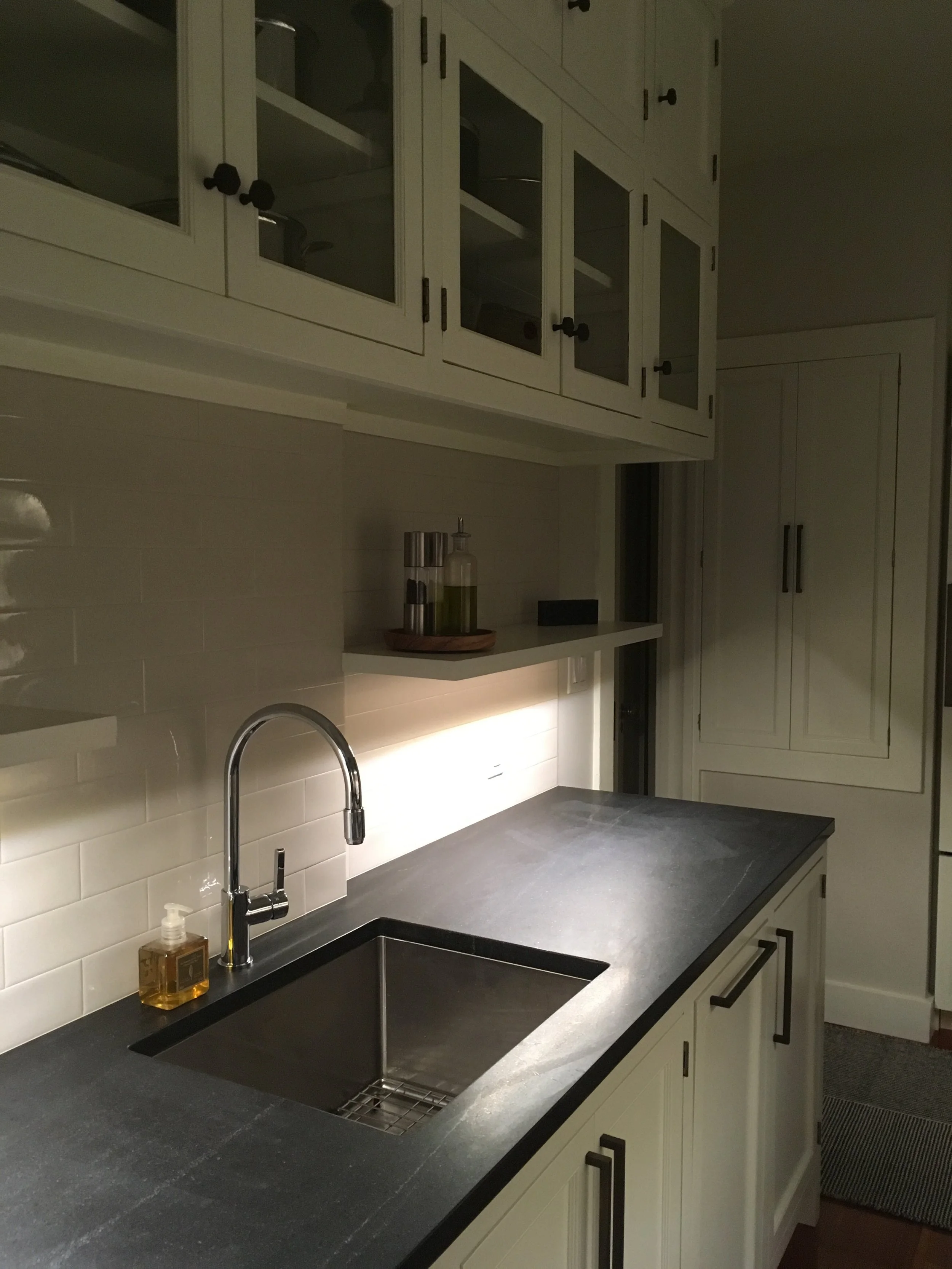  Wanting to create a modern kitchen that was sympathetic to the prewar aesthetic of the apartment. we retained the glass upper cabinets and a well-worn hutch that was refurbished and received new doors. We then inserted new lower cabinets on both 