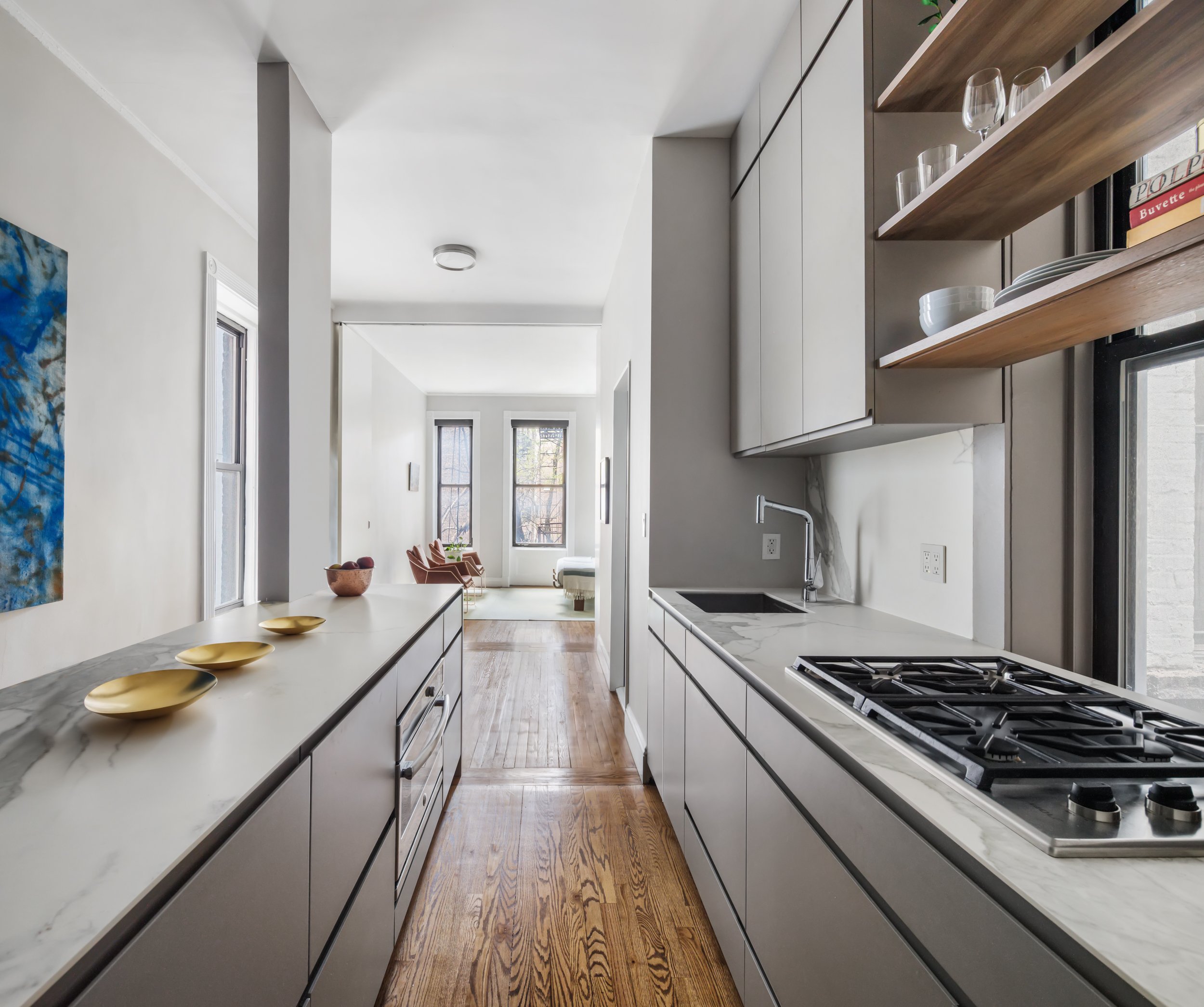 to penetrate deep into the narrow apartment. The first design move was to demolish all of the interior walls of the apartment. Next, we placed the reconfigured open kitchen at the apartment’s center where the homeowner could entertain. A key to the