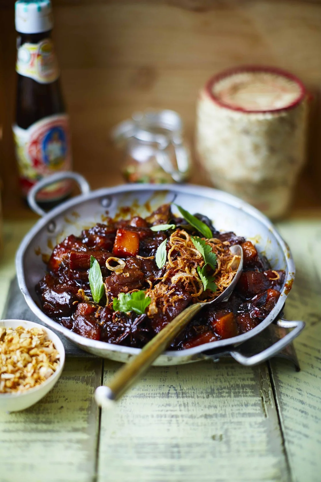 Sticky braised pork belly with roast pumpkin, crispy banana shallots and spring onions in a dark sauce, served in a silver bowl, recipe by Sebby Holmes at Farang London