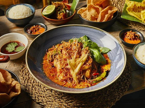Red curry of whole tiger prawns with krachai, fresh green peppercorns and Thai basil in a blue bowl, recipe by Sebby Holmes