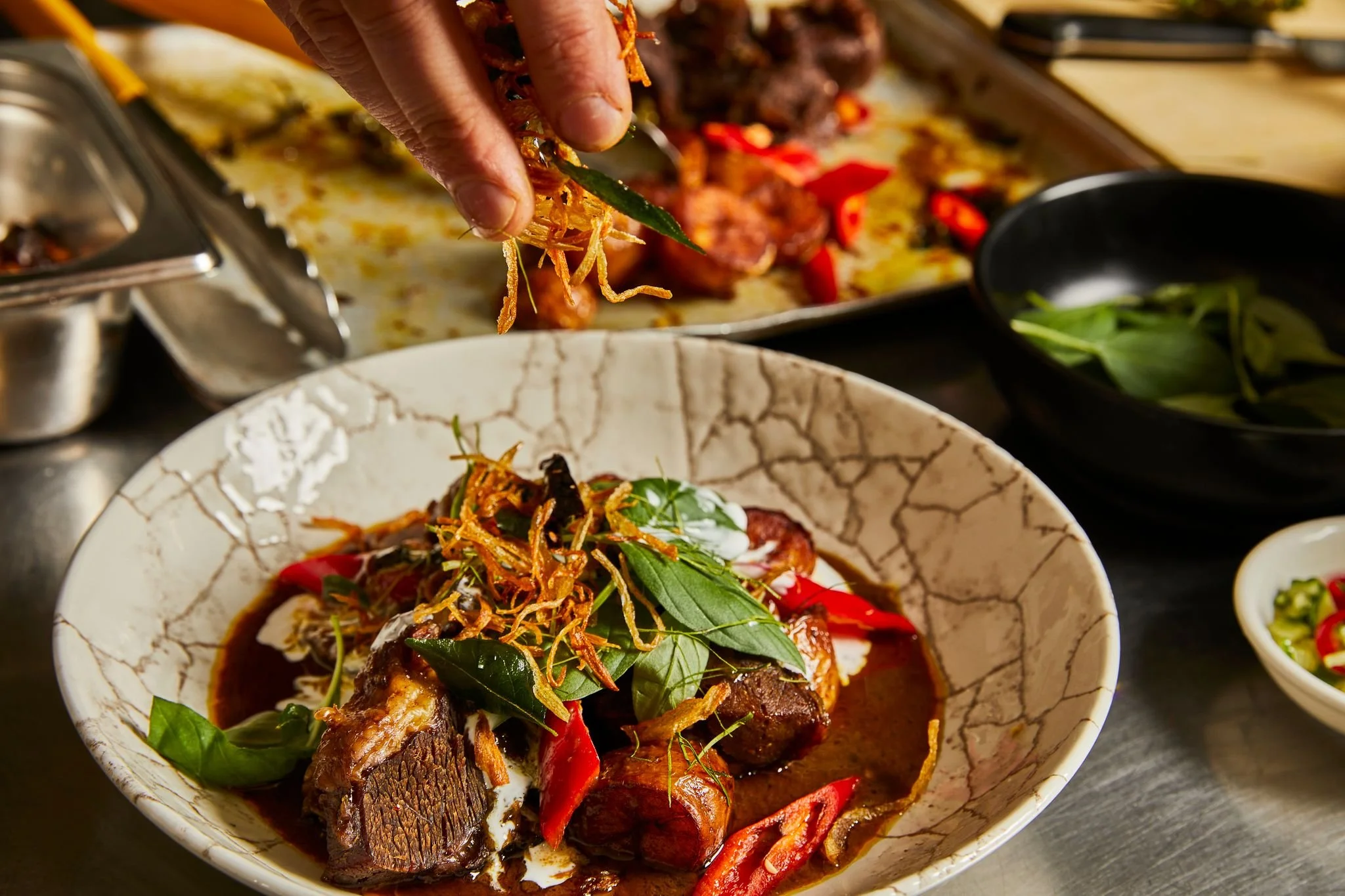 Braised Yorkshire beef cheeks in curry sauce with sweet basil, wild ginger, betel leaves and pickles in a ceramic bowl, recipe by Sebby Holmes at Farang London