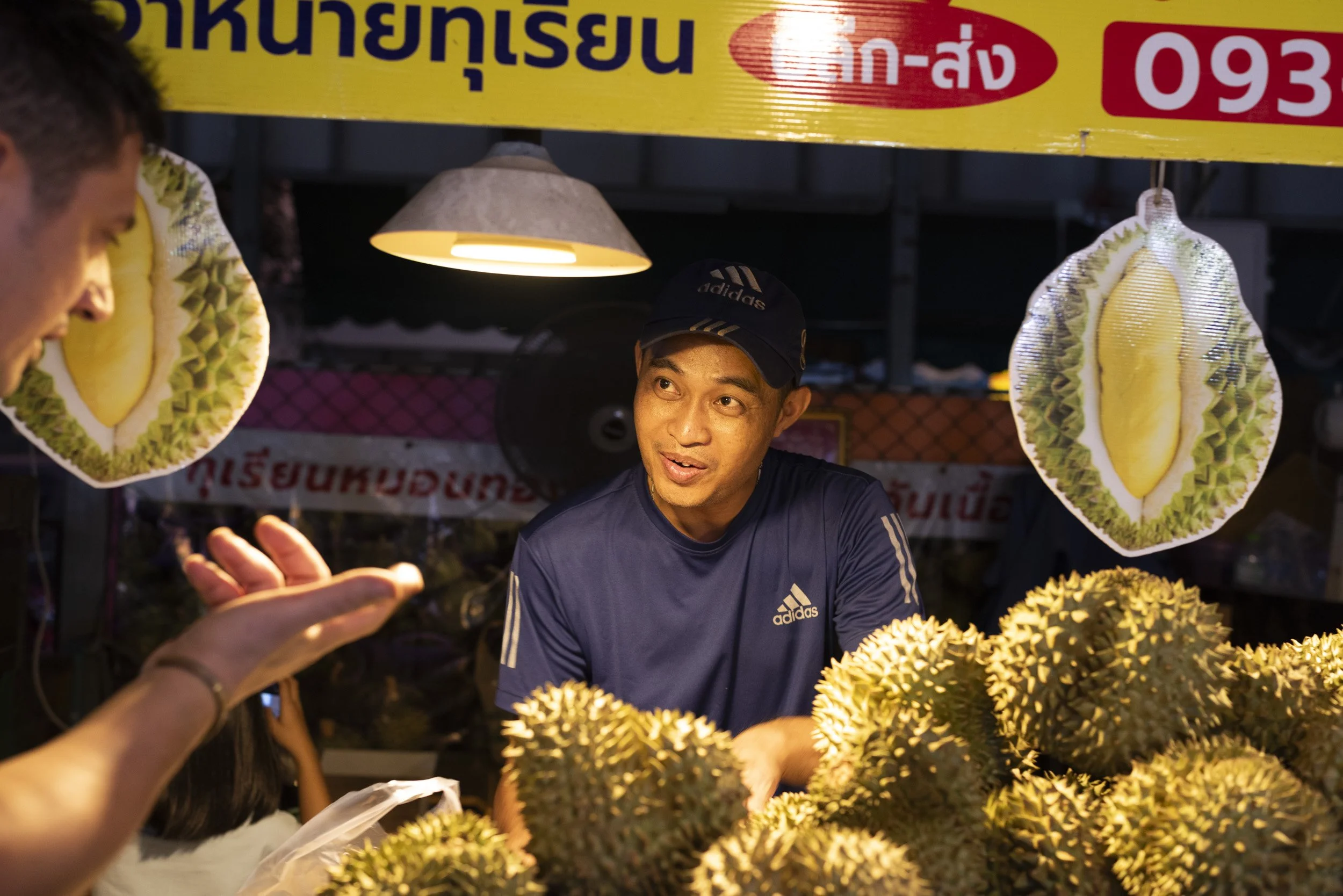 A durian vendor at a Thai night market, photographed on a Farang trip to Thailand, by Sebby Holmes.