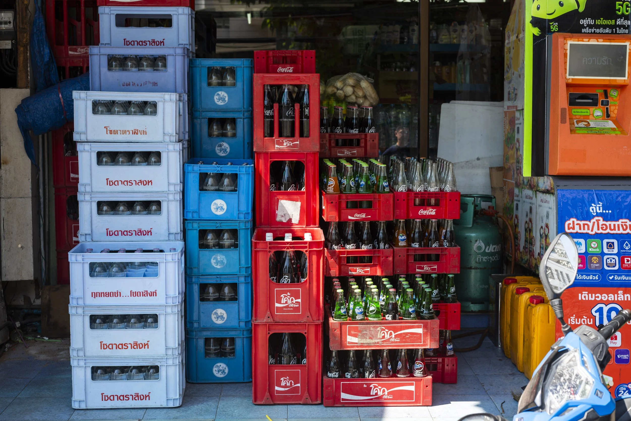 Stacked crates and bottles at a Bangkok market, photographed on a Farang trip to Thailand, by Sebby Holmes.