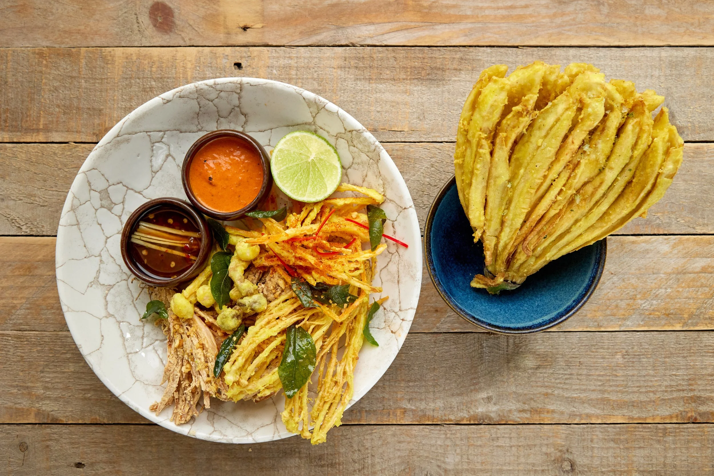 Crispy Singha beer-battered tempura vegetables with crispy curry leaves, chilli powder and dipping sauce on a sharing plate
