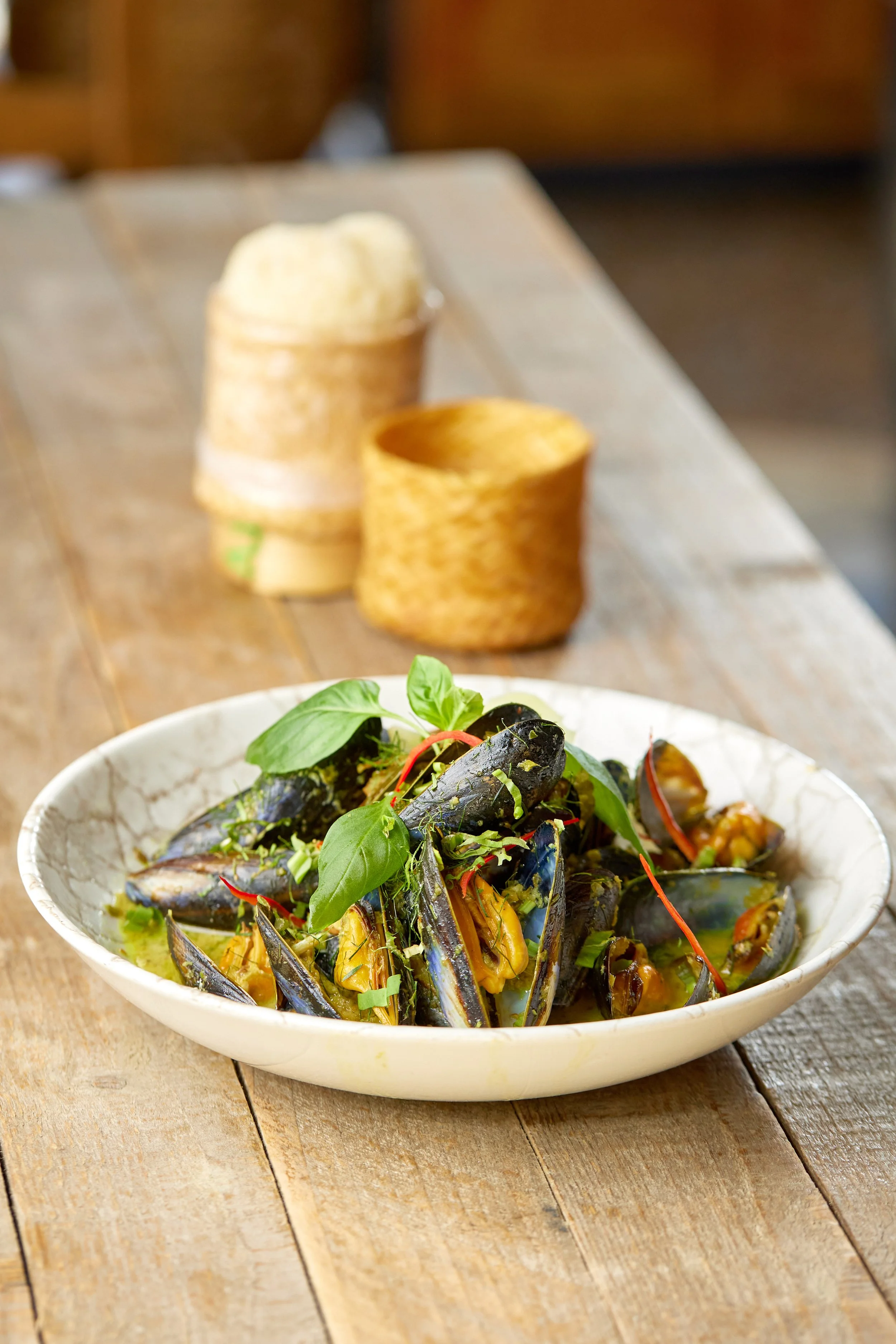Thai green curry mussels in a large bowl with pickled ginger, cucumber, Thai basil and jasmine rice
