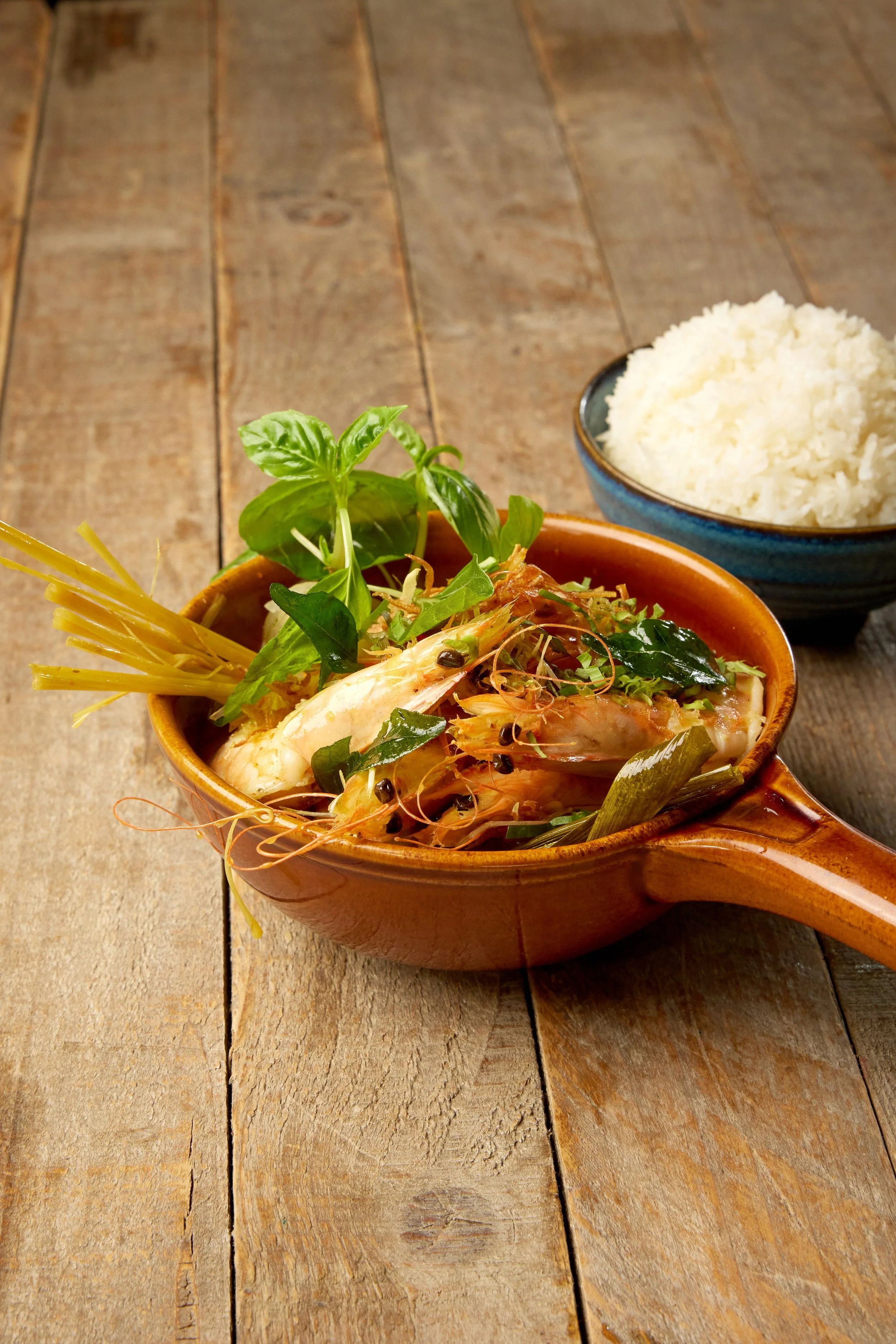 Tiger prawn gaeng gari Thai yellow curry in a bowl with coconut milk, green beans, crispy shallots and curry leaves