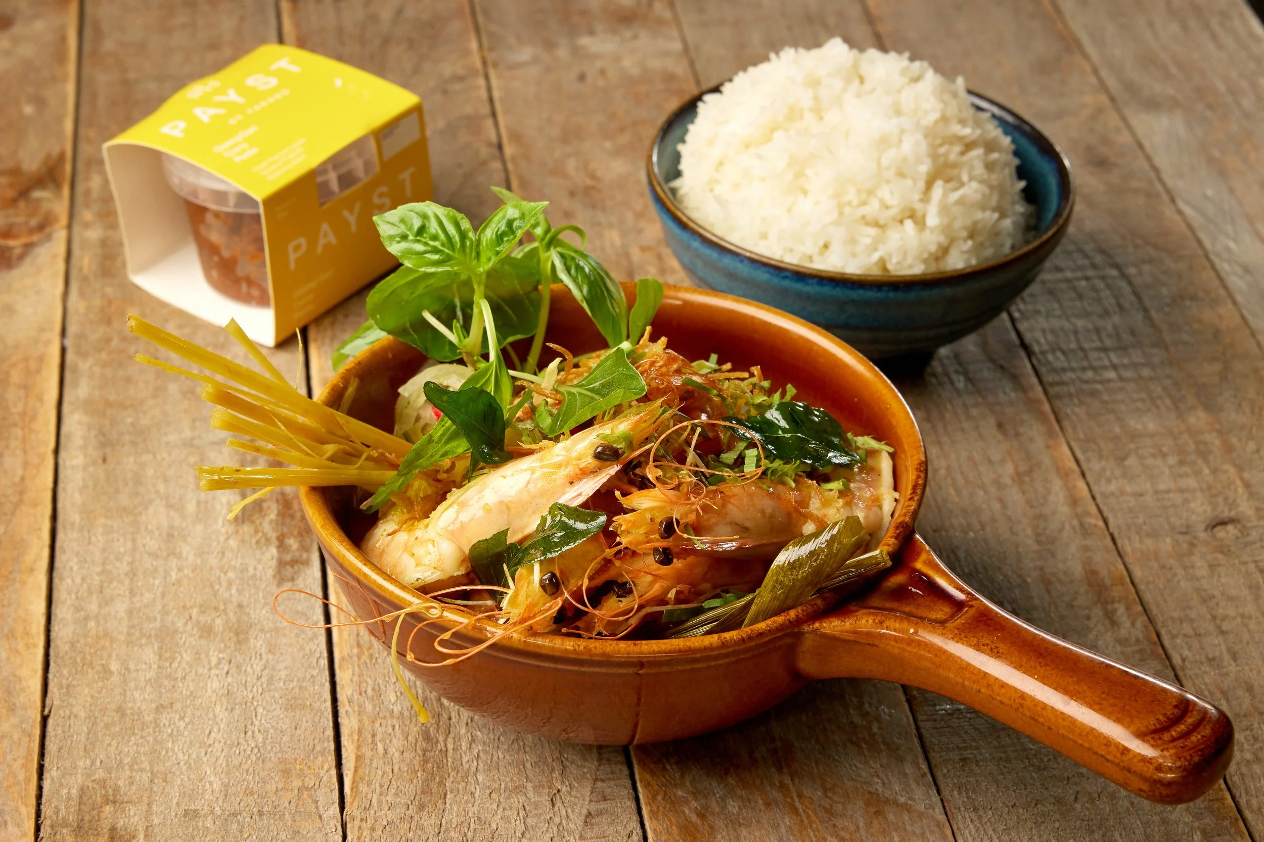 Tiger prawn gaeng gari Thai yellow curry in a bowl with coconut milk, green beans, crispy shallots and curry leaves