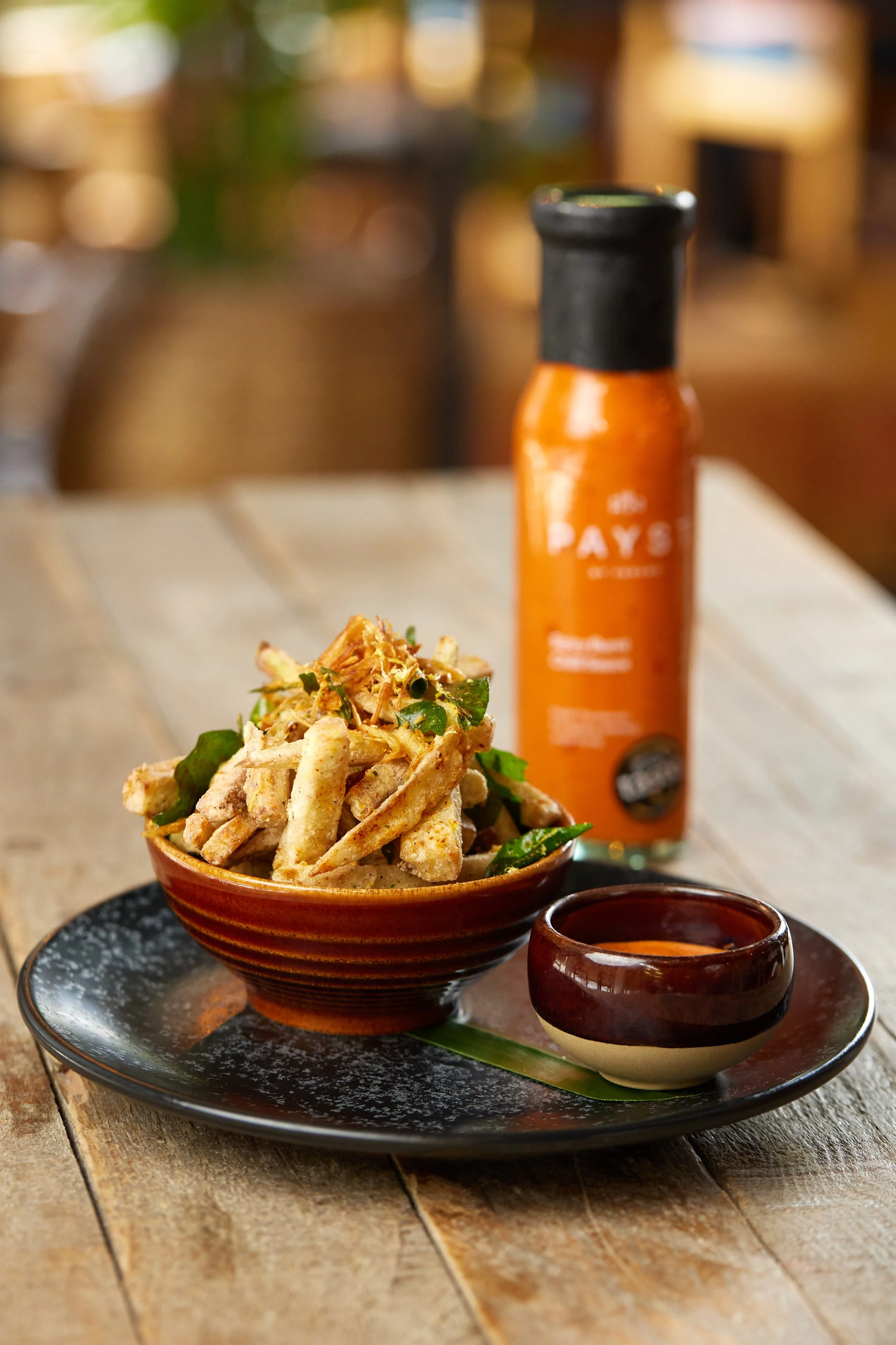 Crispy aubergine nibbles with chilli powder, lemon zest and crispy shallots on a serving plate