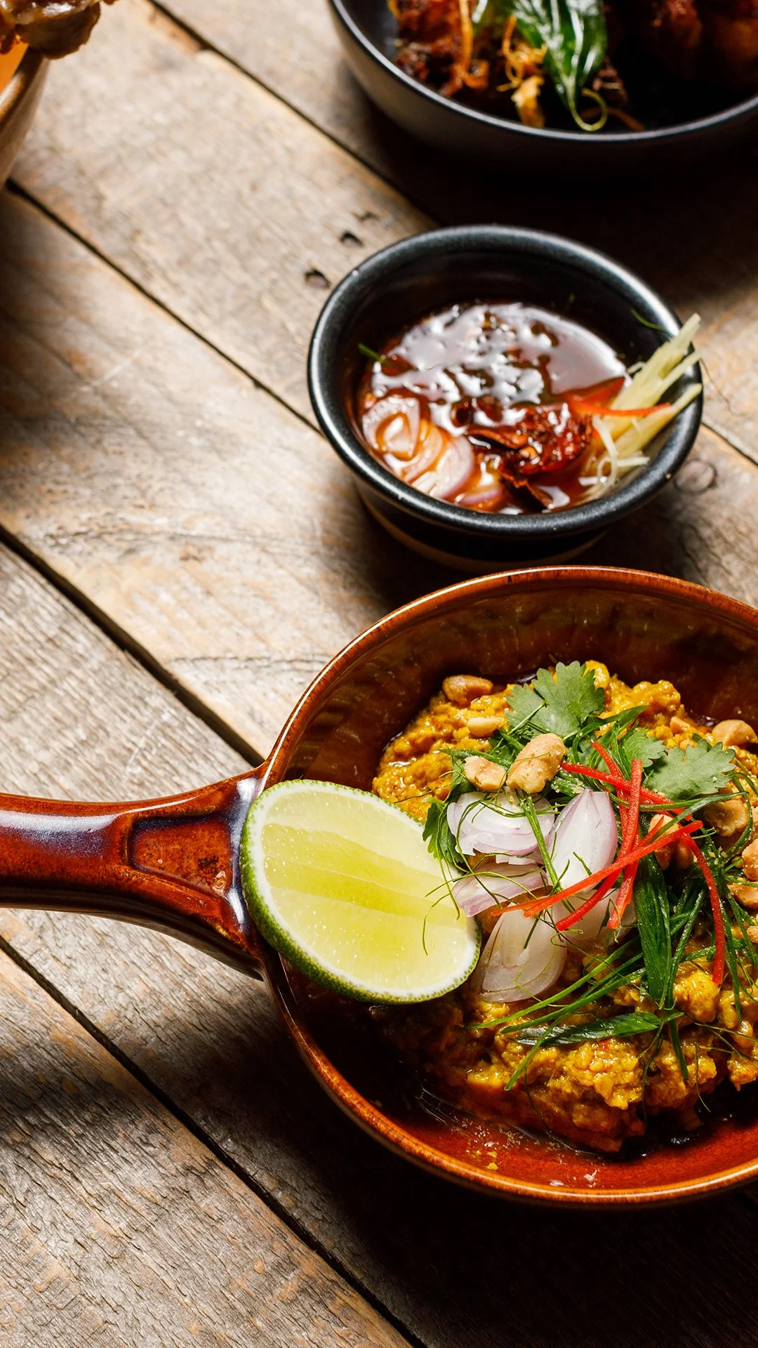 Minced chicken satay relish in a clay bowl with fresh coriander, sliced red chilli and toasted peanuts, recipe by Sebby Holmes