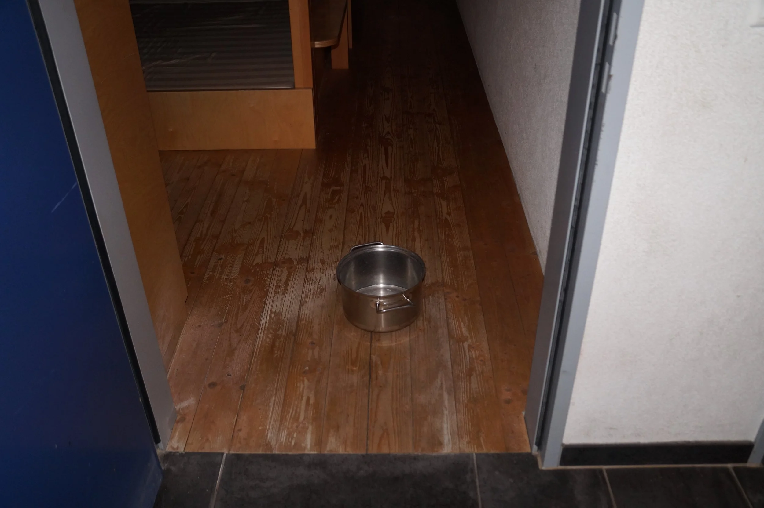  Ein Kochtopf fängt, das von der Decke tropfende, Wasser aus dem Wasserschaden auf. 