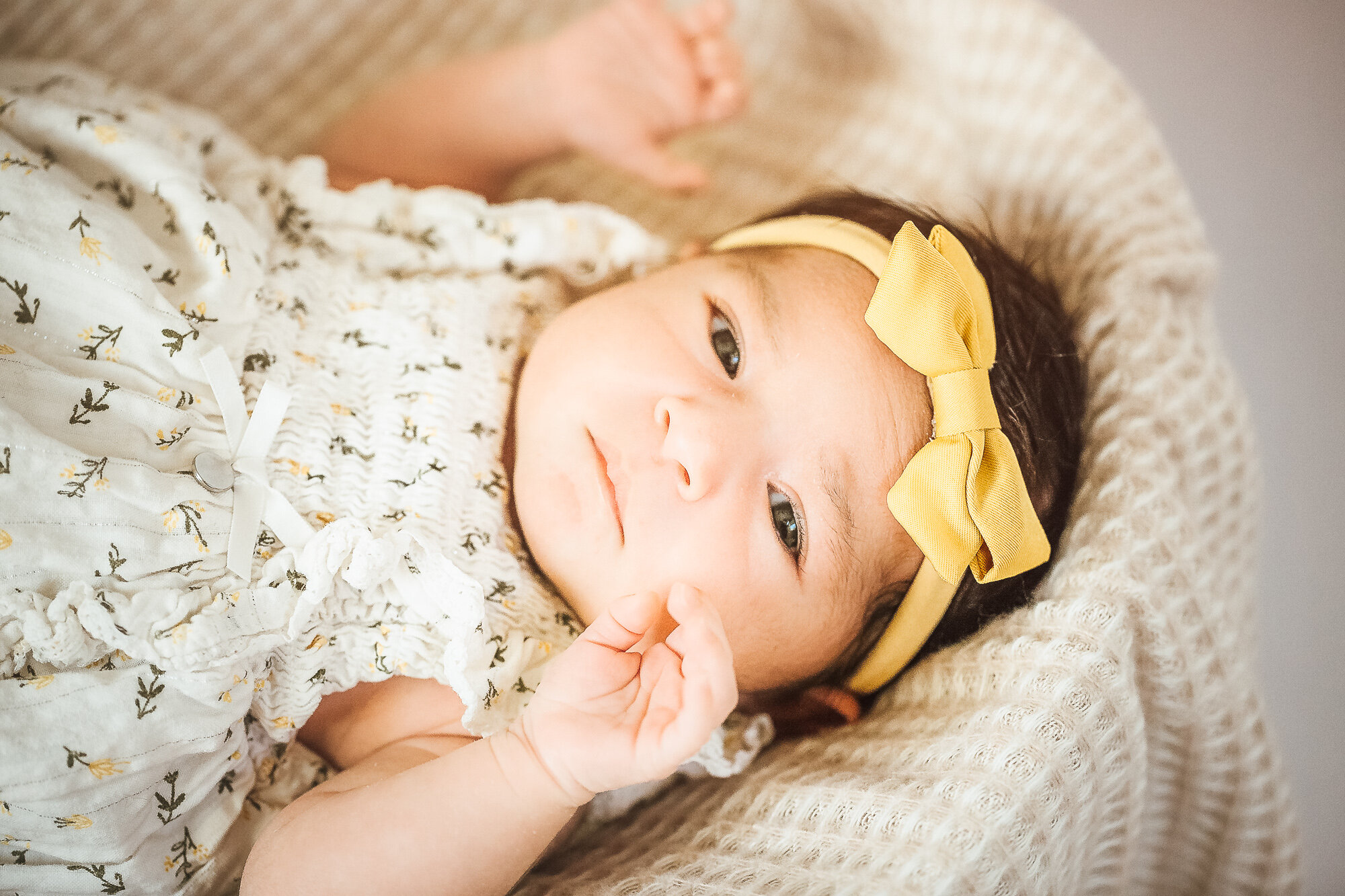 Newborn baby girl awake with hands by her face