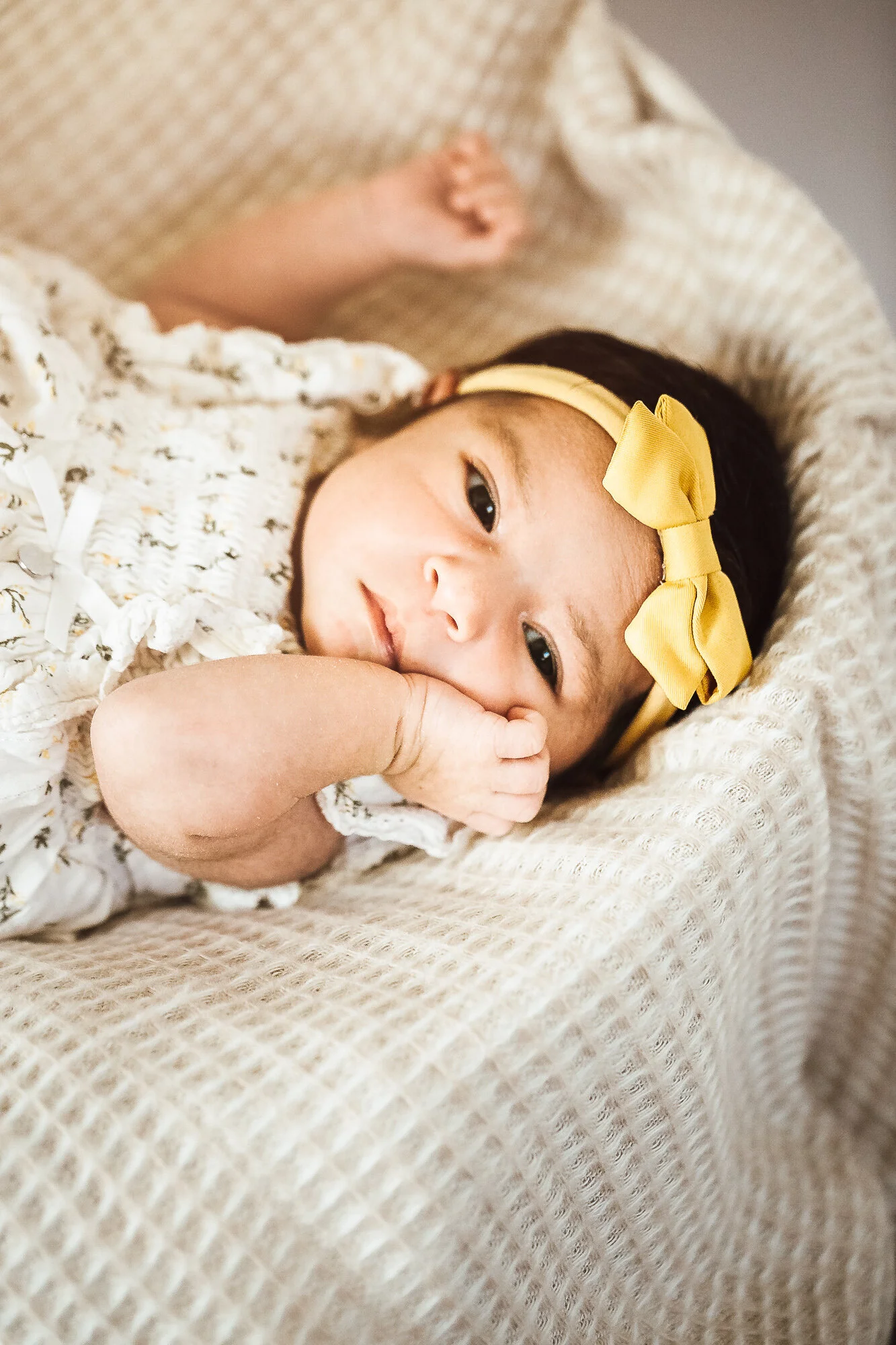 Newborn baby girl awake with hands by her face