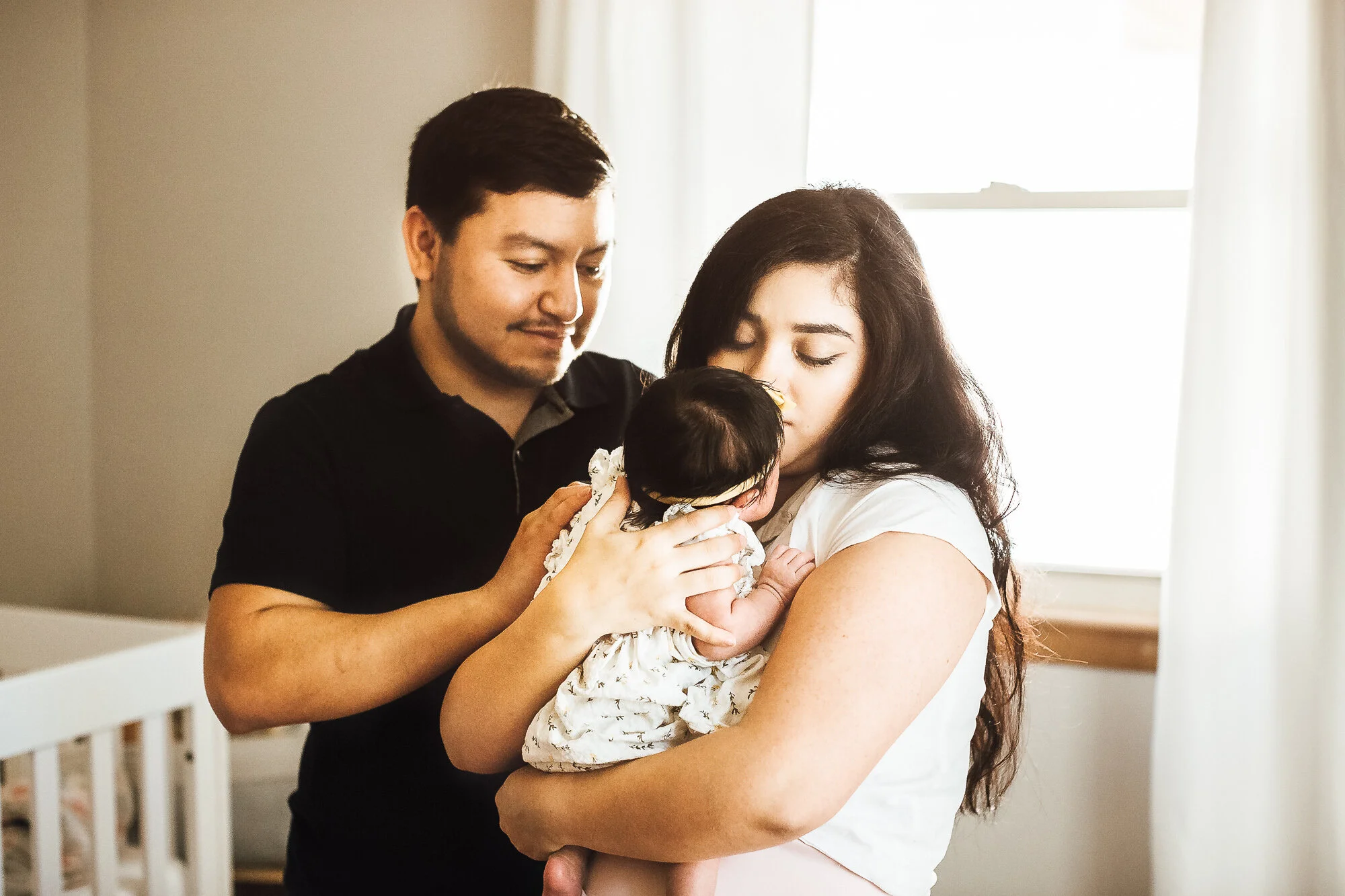 Newborn baby girl being held by mother while father stands near by