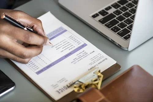 Man holding a pen going through a list of documents to be completed.