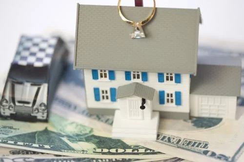 a-car-and-a-house-with-wedding-ringing-on-top-sitting-on-dollar-bills .jpg