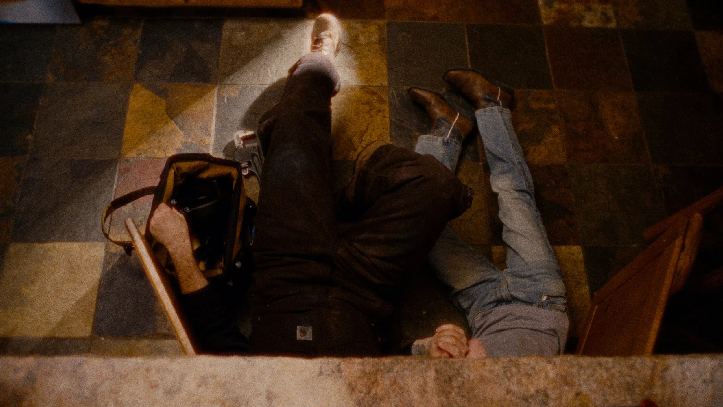 A person lying on the floor with another person lying across their chest, appearing to perform CPR.