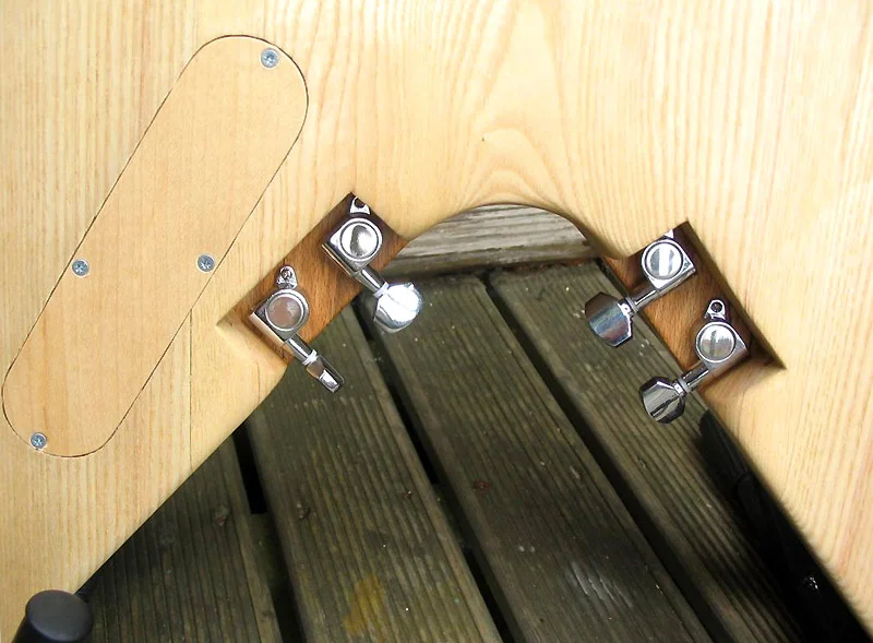 Mounting position of the four tuners on the body and the laminated maple veneer cover for the control cavity.