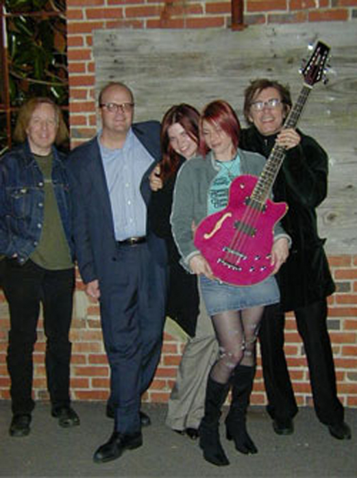 Shalini receiving a Waterstone 12-string bass. Left to right: Mitch Easter, Bob Singer of Waterstone, Alison Petersson, Shalini, Tom Petersson.