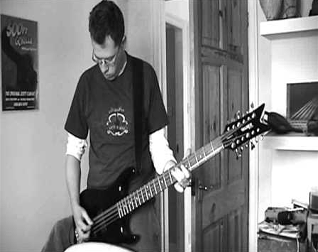 Neil Lough with his Hamer CH-12 12-string bass. A 300 Ft Gorilla poster is in the background.
