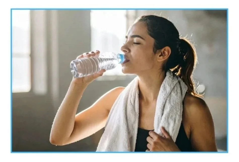 Eine Frau die Sport gemacht hat trinkt aus einer Wasserflasche