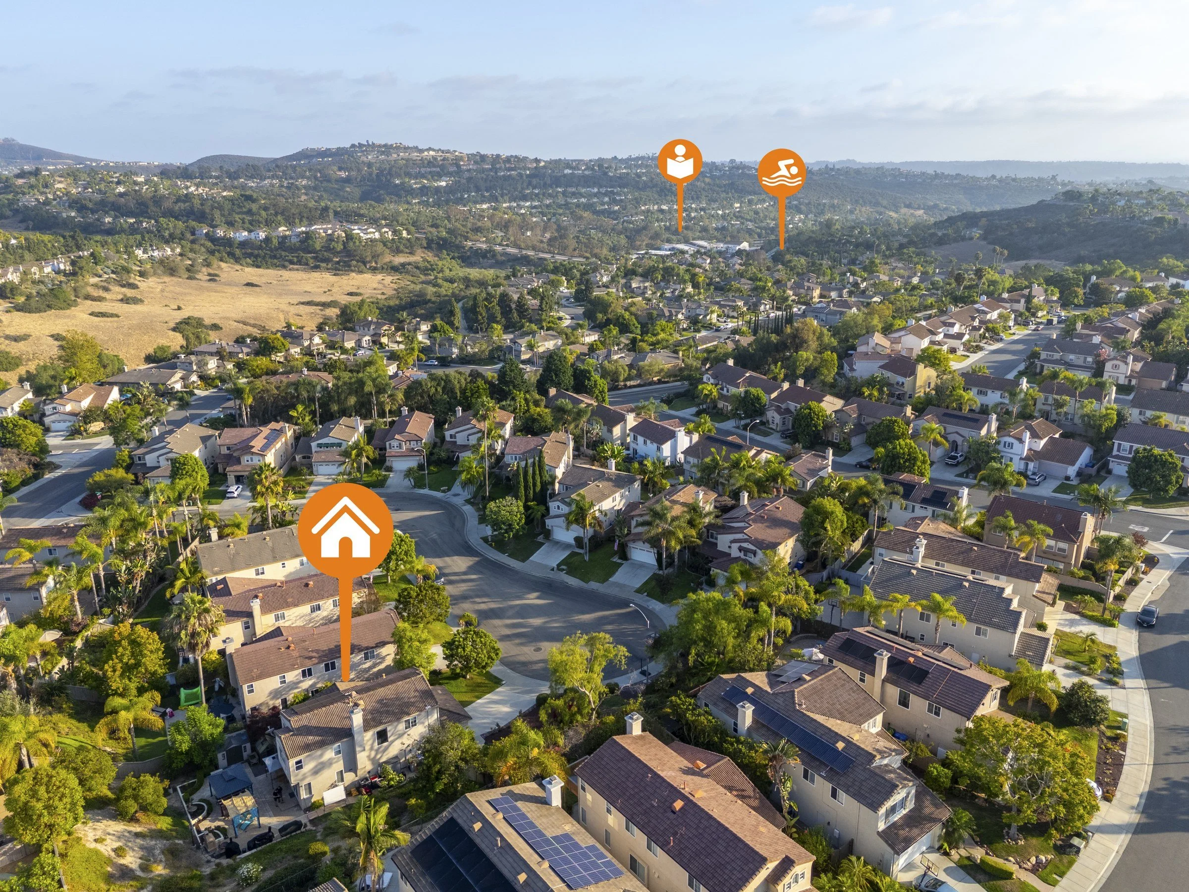Drone aerial of a La Costa neighborhood in Carlsbad with map pins marking the listing, a school and a community pool
