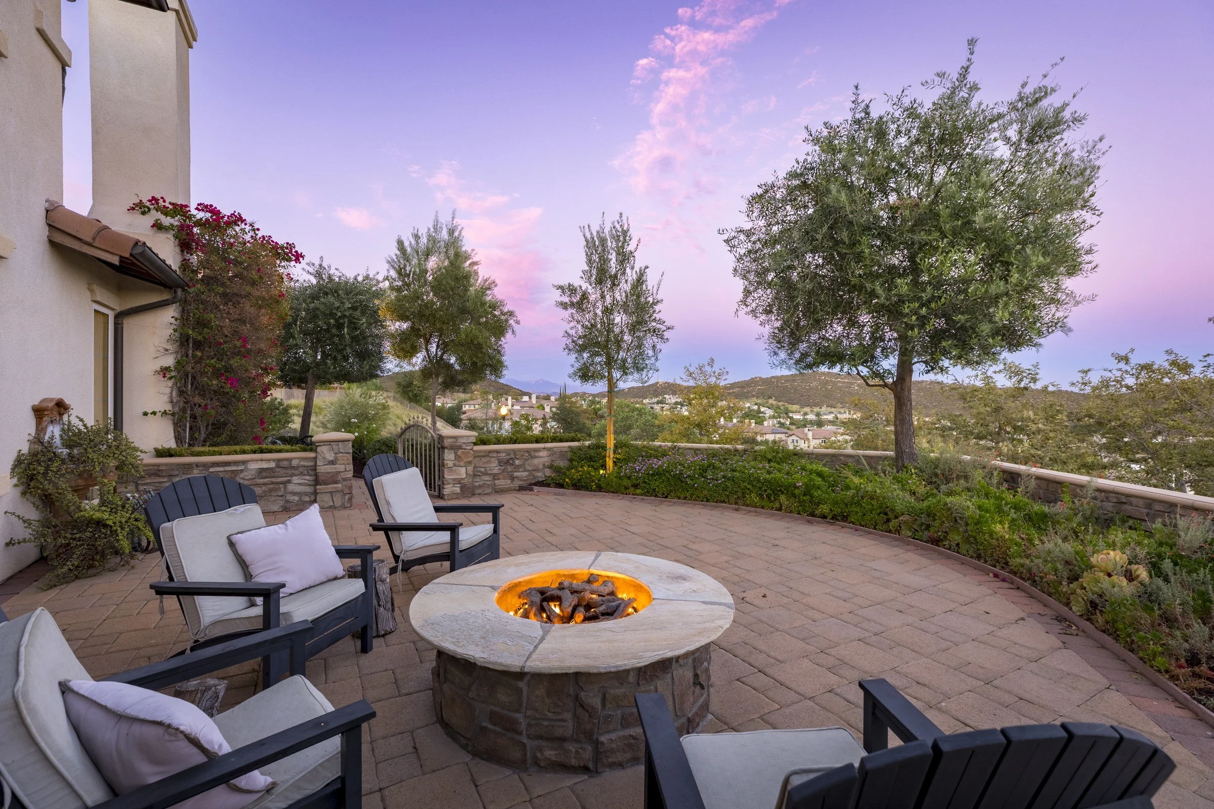 Backyard patio with a fire pit and seating overlooking rolling hillside views at dusk