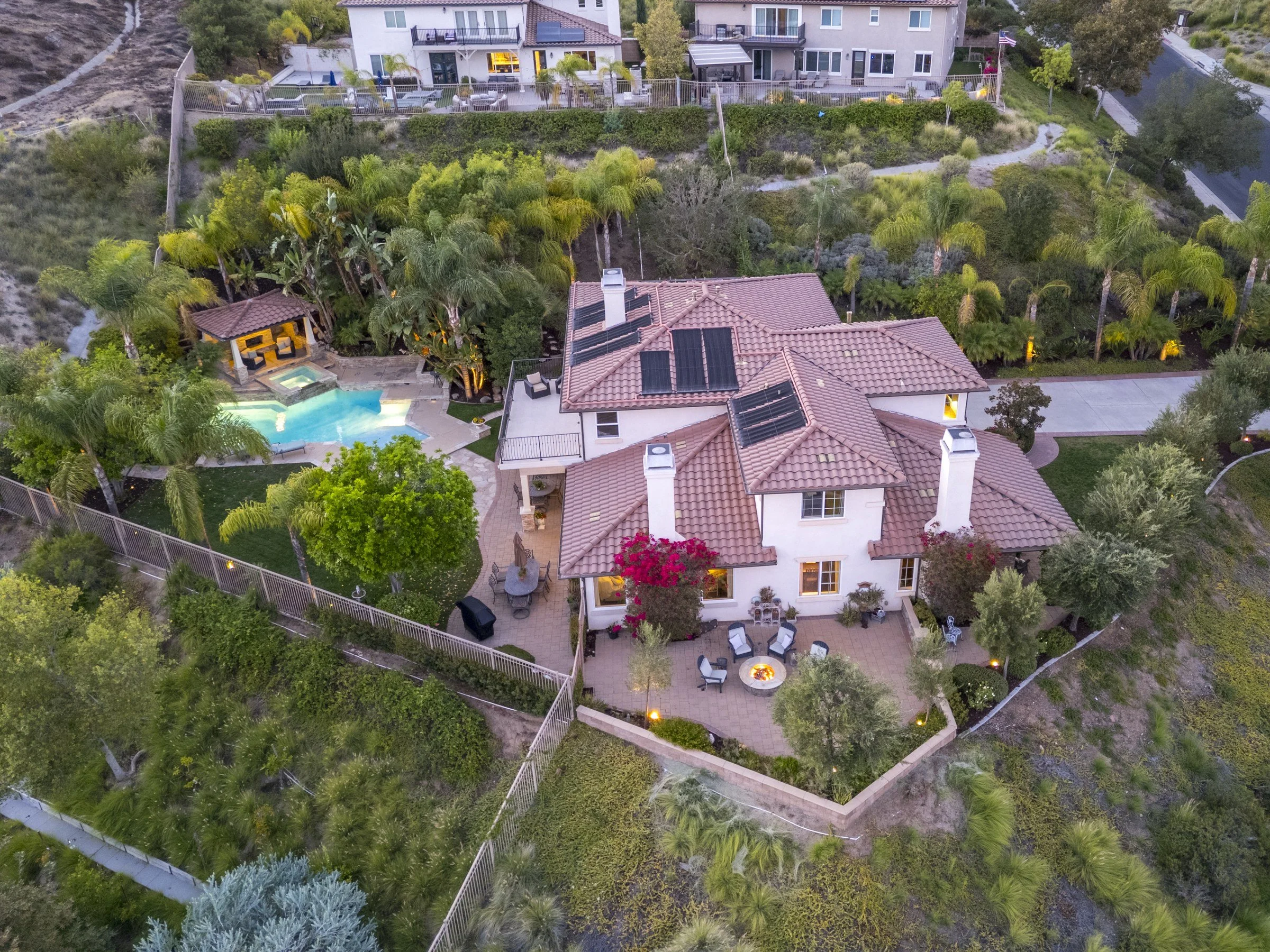 Drone aerial of a hillside home on a large lot with a pool and mature landscaping at dusk