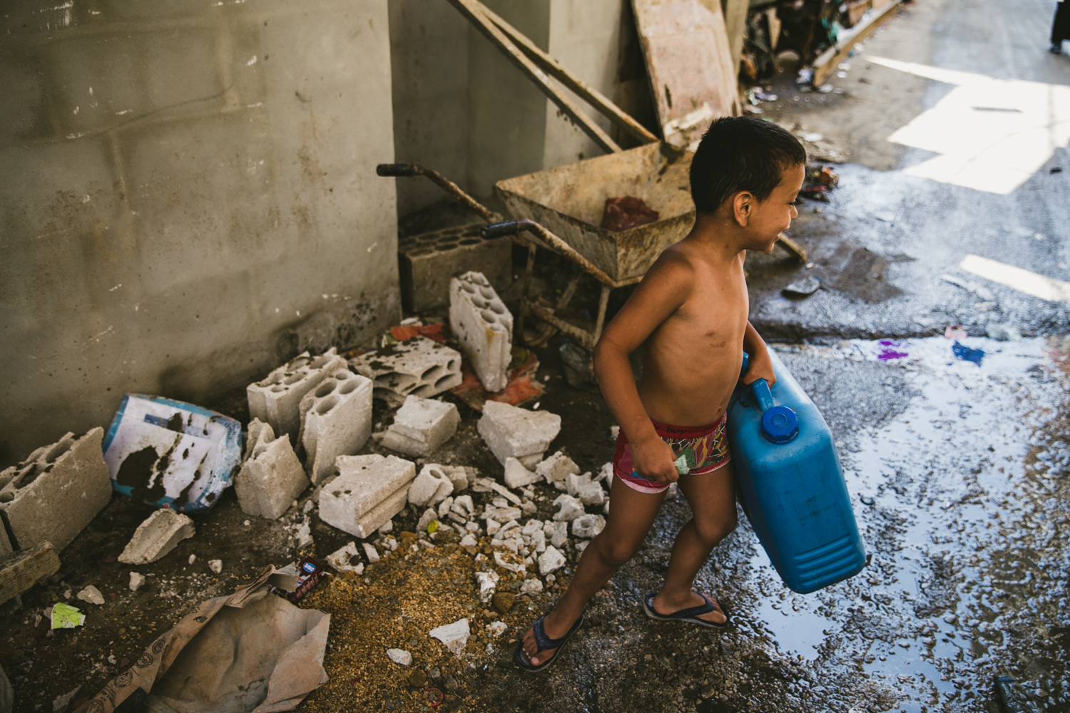  A small child carrying a water can down an alley in&nbsp;Shatila. 