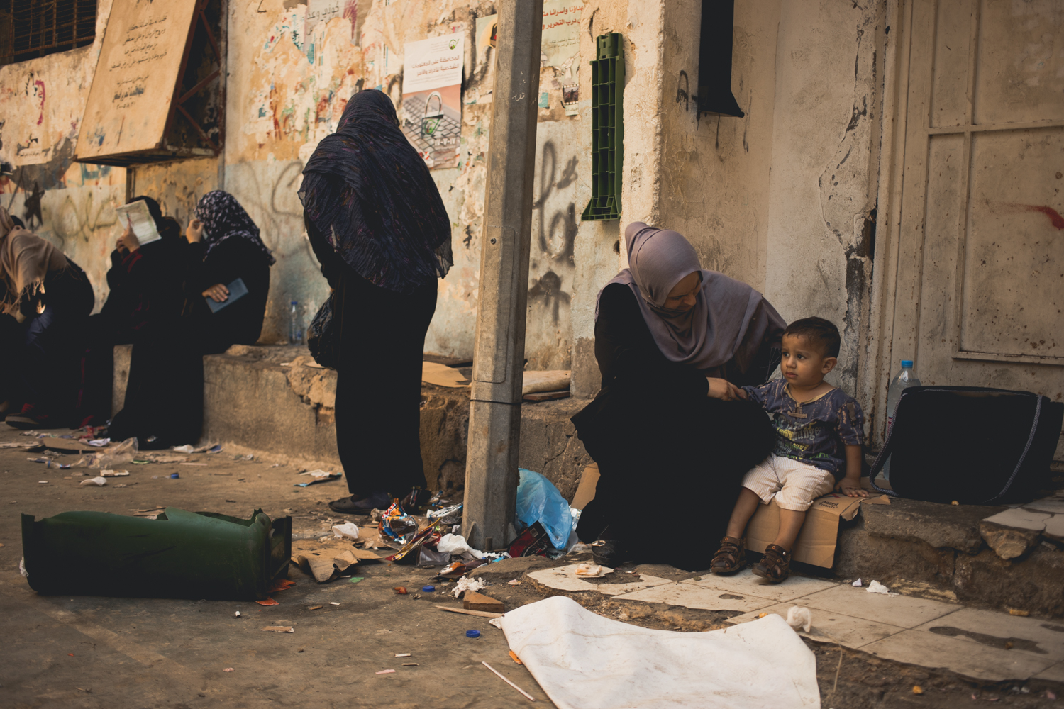  Mothers and children wait near the office of the PLO inside Shatila. 