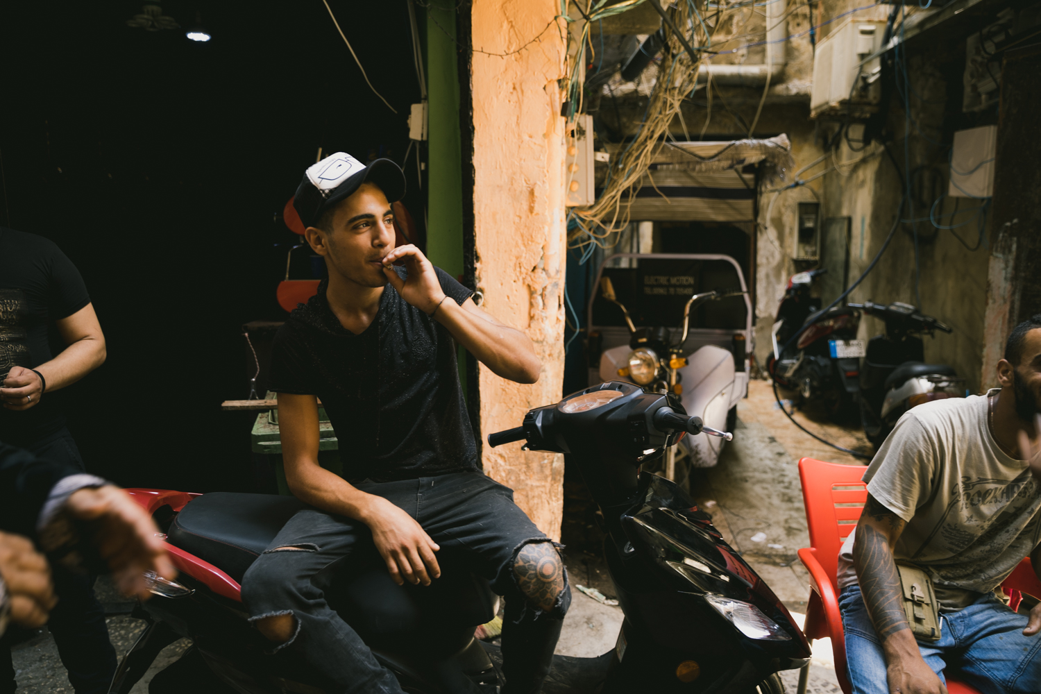  A young Palestinian man smokes a cigarette while hanging with friends during the middle of the day. Due to complications with the legal and social status of Palestinians in Lebanon, most people in the camps struggle to find work, and thus spend good