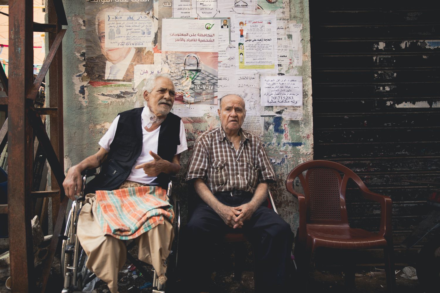  Two elderly Palestinians sit and talk on a street corner inside Shatila. 