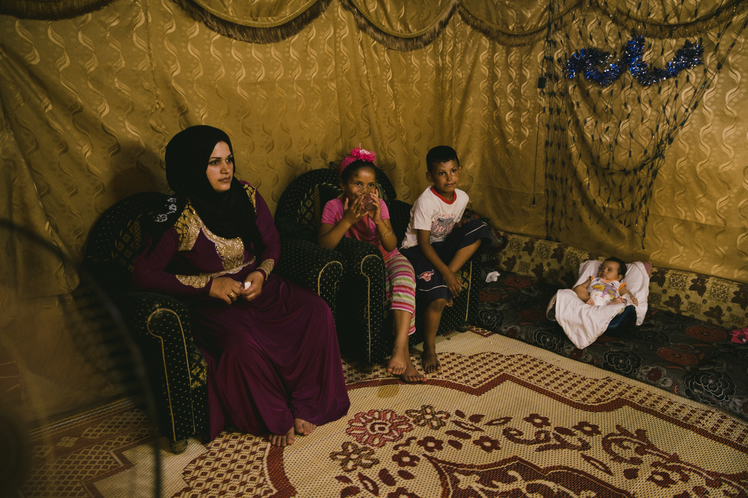  A young mother sits with her children in their tent inside the Sad Nail camp in the Bekaa Valley. 