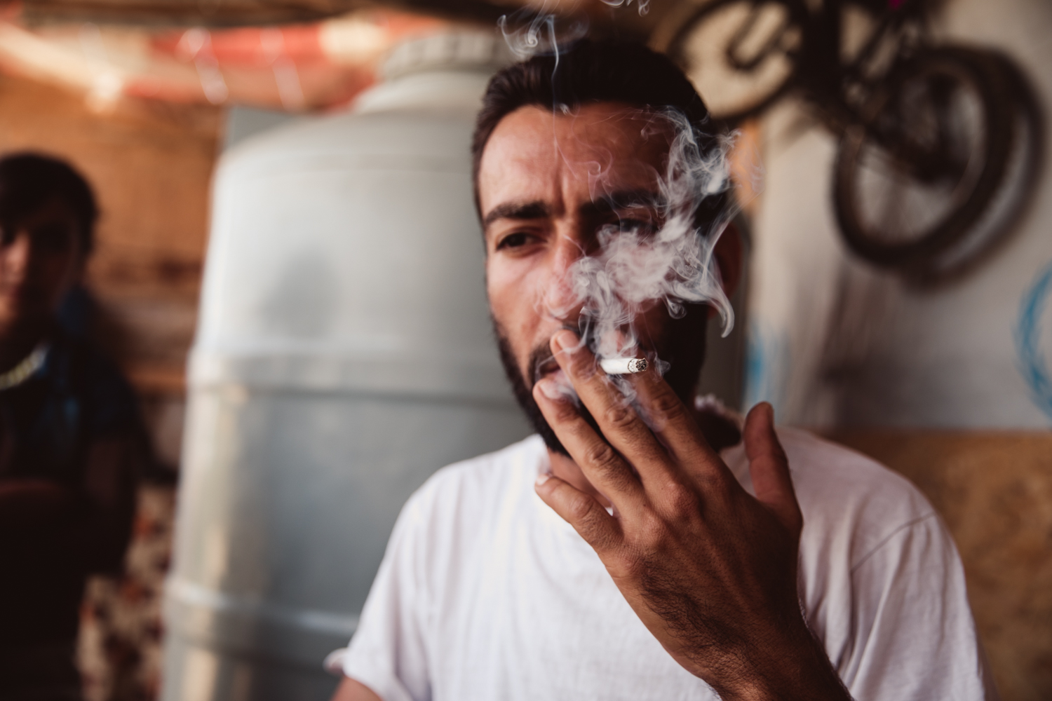  A Syrian refugee smokes and drinks tea outside the tent he and his family share. 