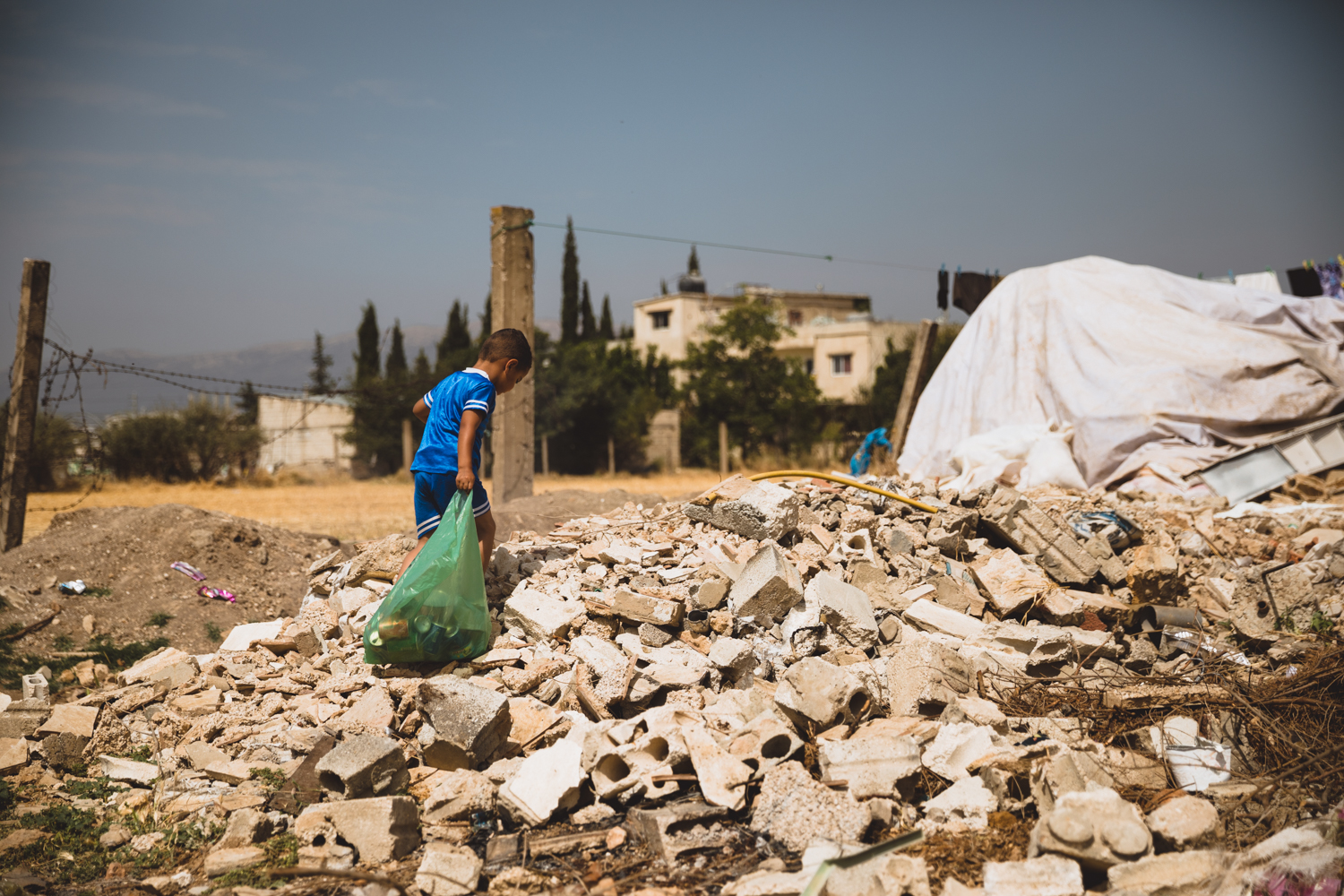  A young child drags trash across a&nbsp;rubble pile in a small camp in the Bekaa Valley.&nbsp; 