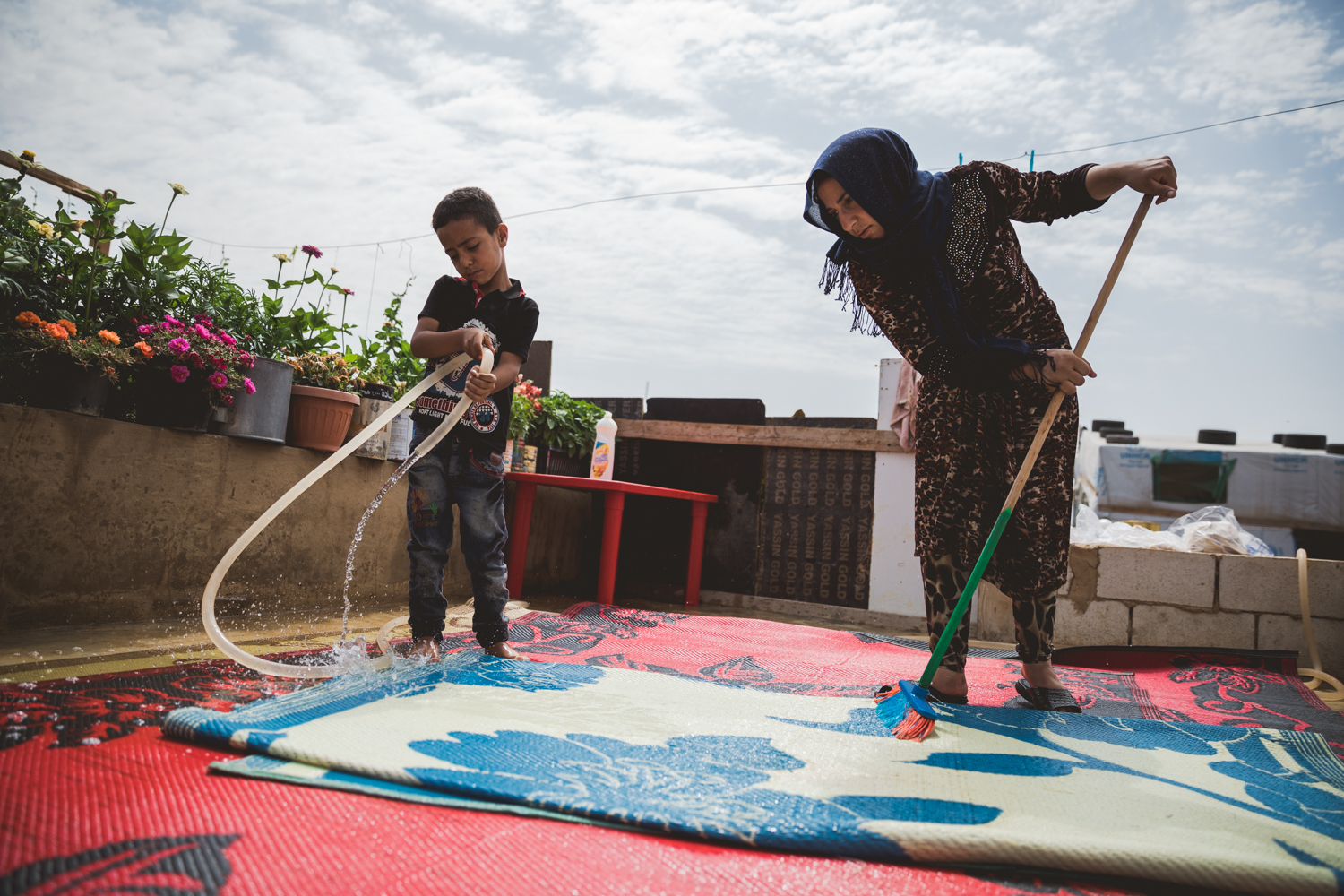  A young boy and his mother cleaning the rugs of their tent. 
