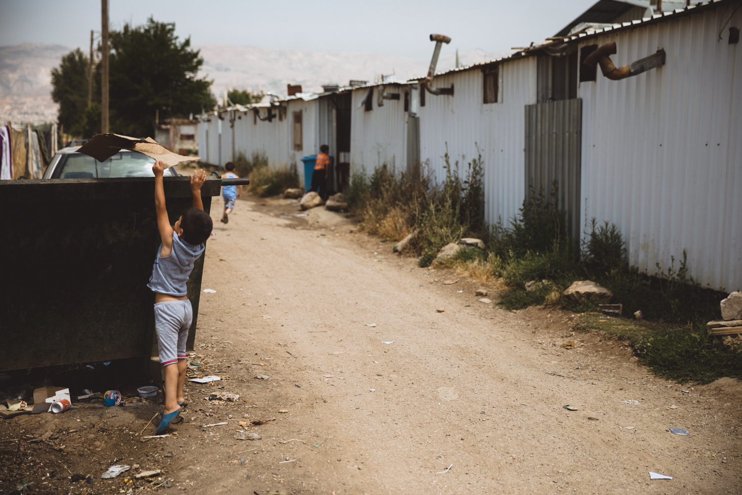  A boy throws out trash outside the steel refugee compound he lives in.  