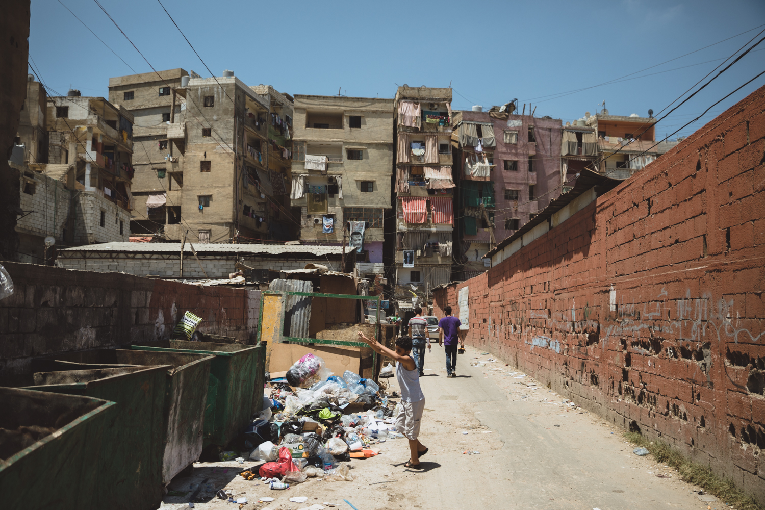  A child throws garbage into dumpsters outside the entrance to&nbsp;theShatila refugee camp. 