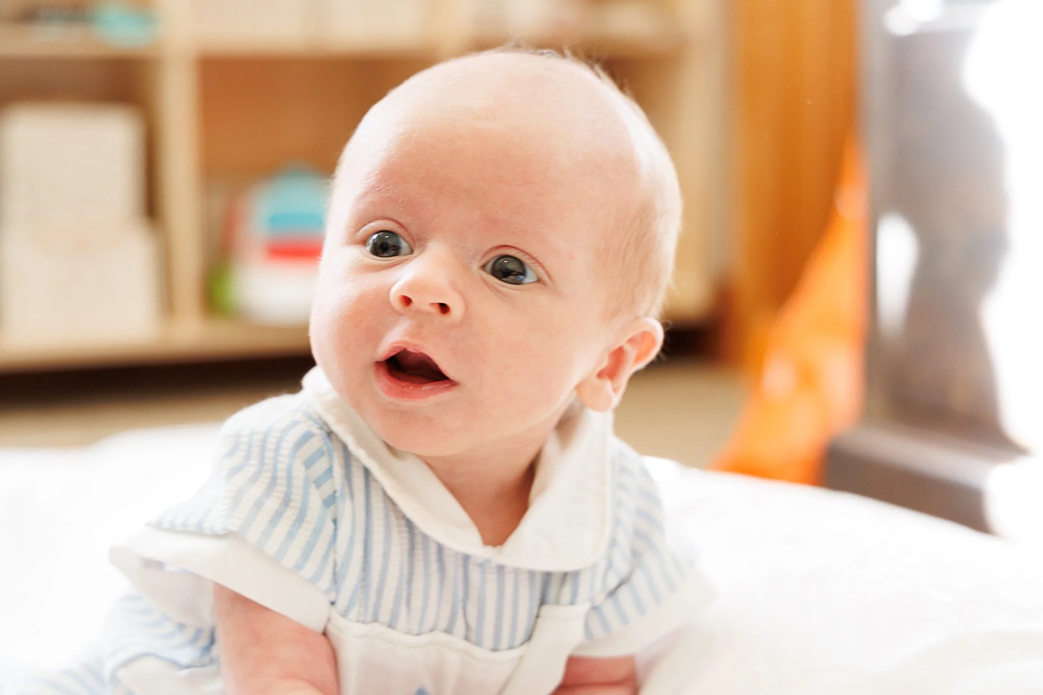 Baby in blue and white outfit lying on a bed.