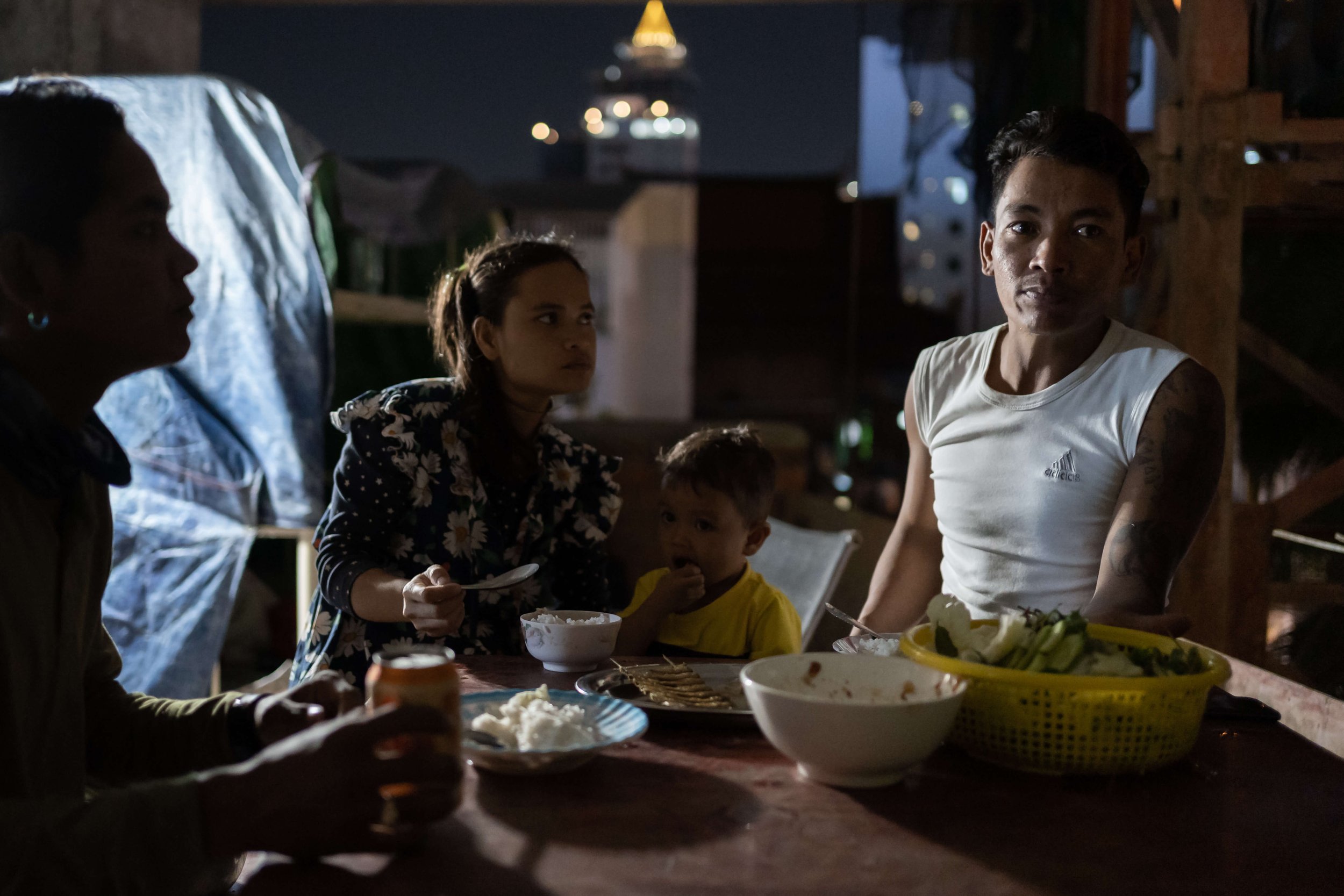  Construction worker Ma Srieng and his wife Som Theary eat dinner on the 3rd floor of a half-built 18th-floor condominium where they live in the heart of Phnom Penh. They live onsite with their 2-year-old son and Srieng’s cousin Dieb Phearum. Like ma