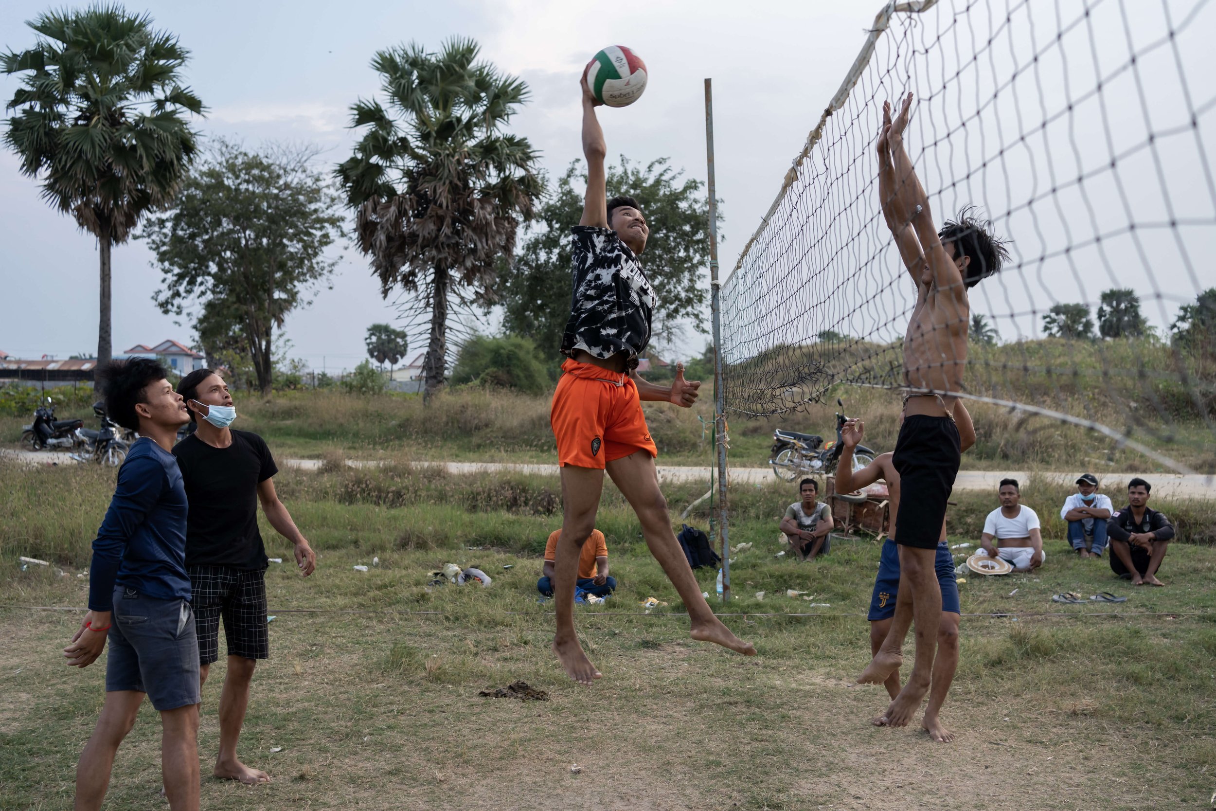  After finishing work, Sun Kim Yan, Sim Ry, Dieb Phearum, Phan Sochantra, and Sim Rib play volleyball with other construction workers at a field in Kambol district. Sim Ry says they play volleyball to build “strength and solidarity” within the team a