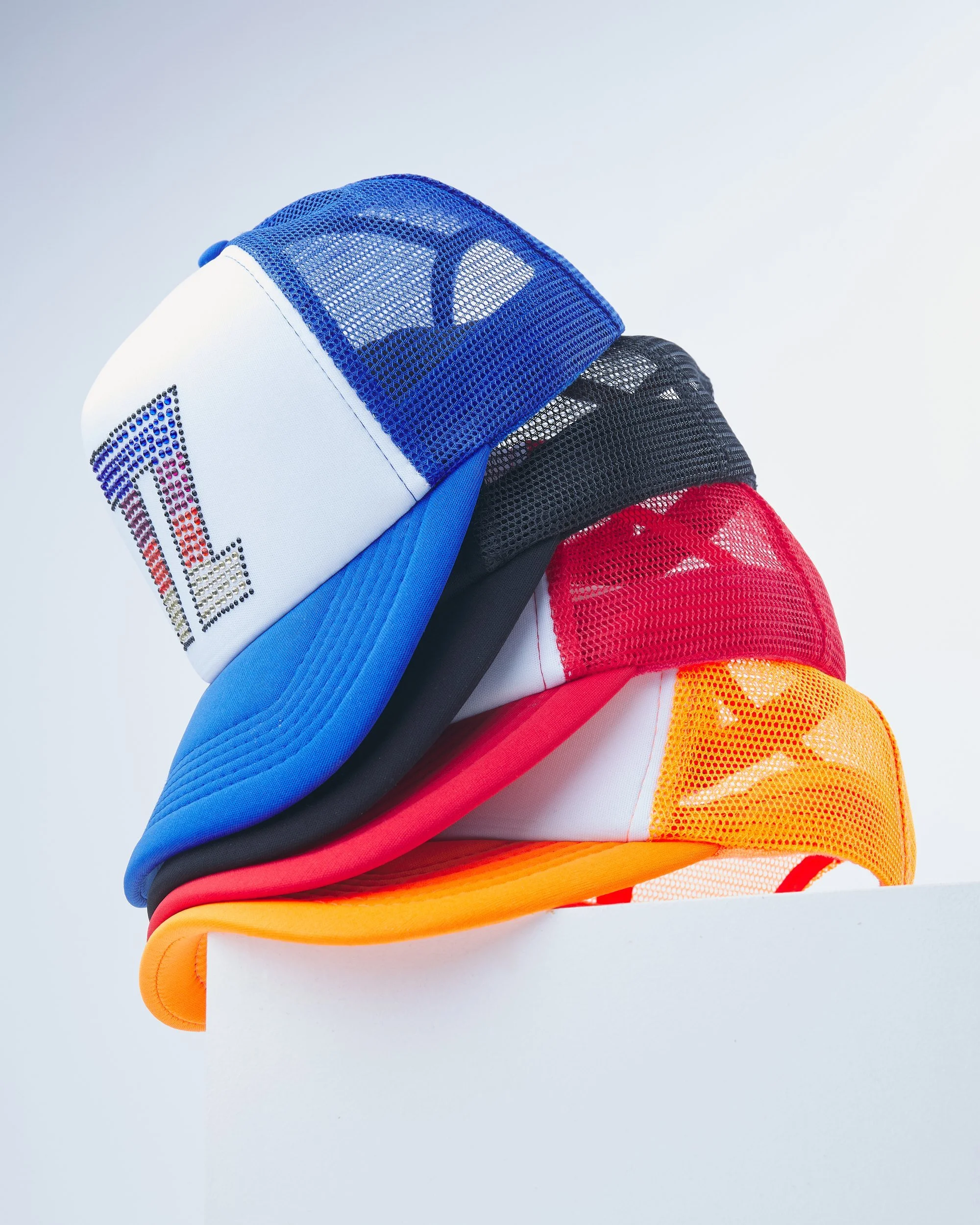 Blue, black, red and yellow baseball caps arranged in a layered product composition.