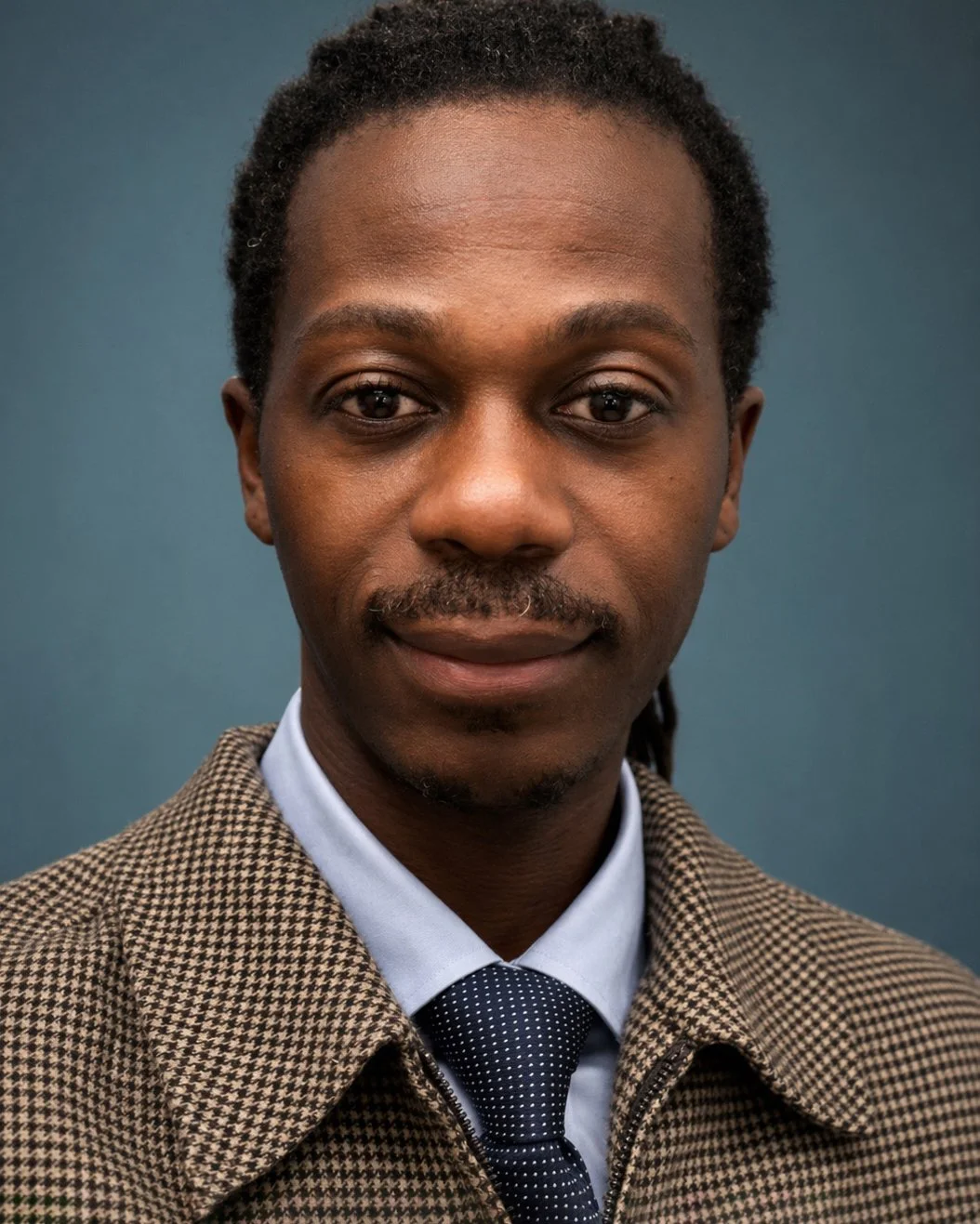 Editorial portrait of a male model in a checkered brown blazer and navy tie, commercial photography by Seltosamarts Photography NYC.