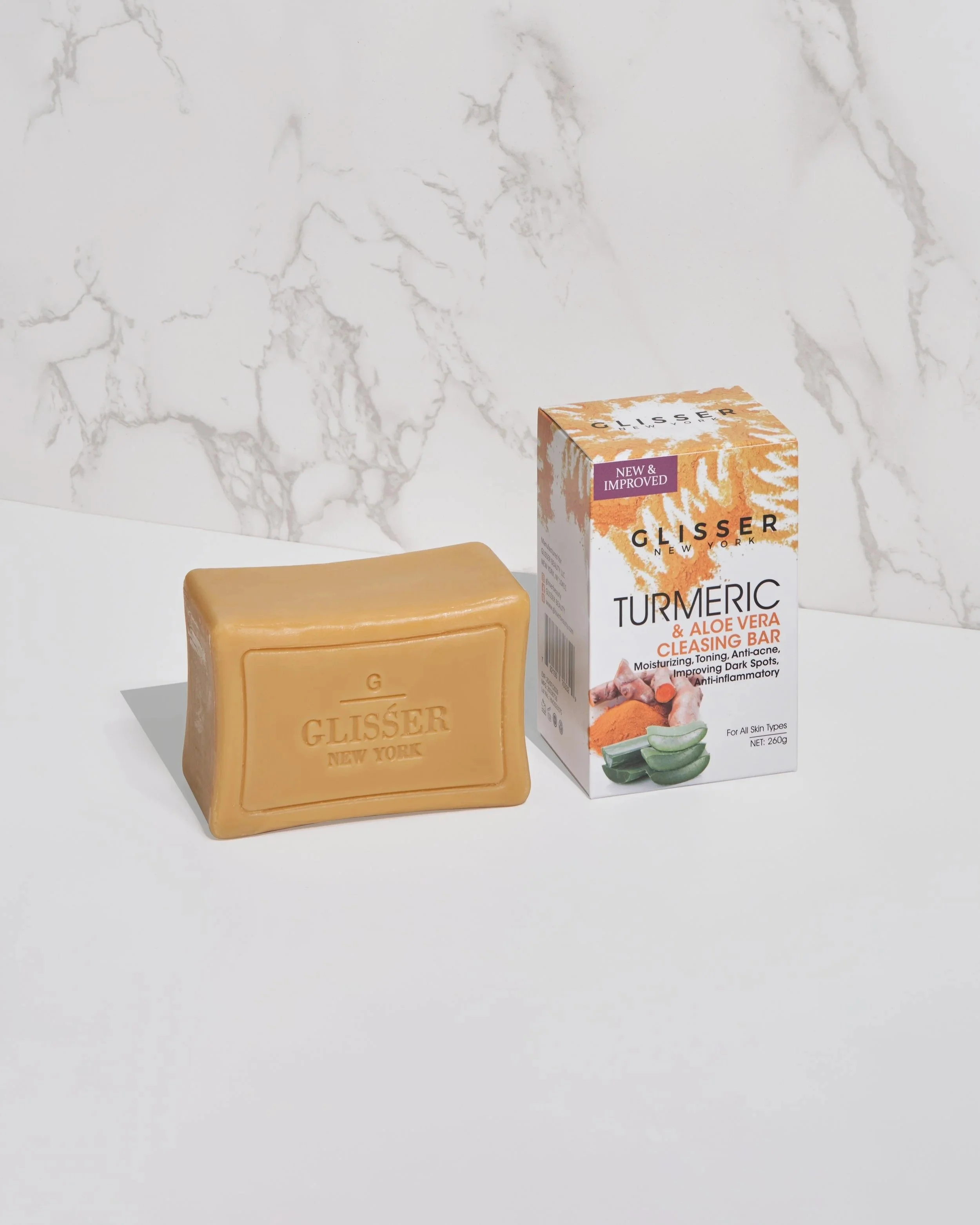 Glisser cleansing bar and packaging arranged with aloe vera and turmeric on a white surface.