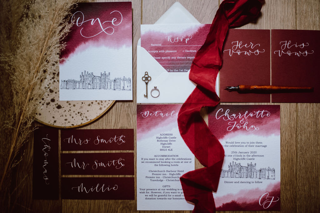 Burgundy watercolour and Highcliff castle illustration wedding wedding invitation suite with matching table numbers, vow books and place cards.jpg