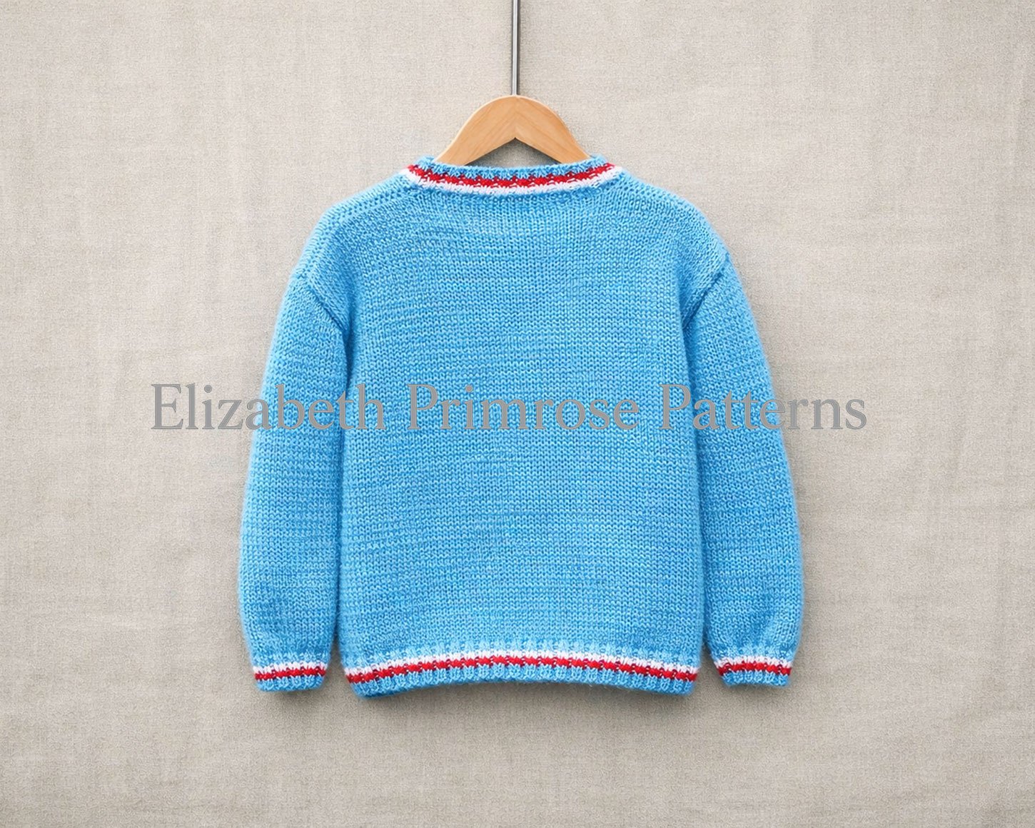 Light blue hand knitted jumper back view on wooden hanger, red white striped collar and cuffs on beige linen background.