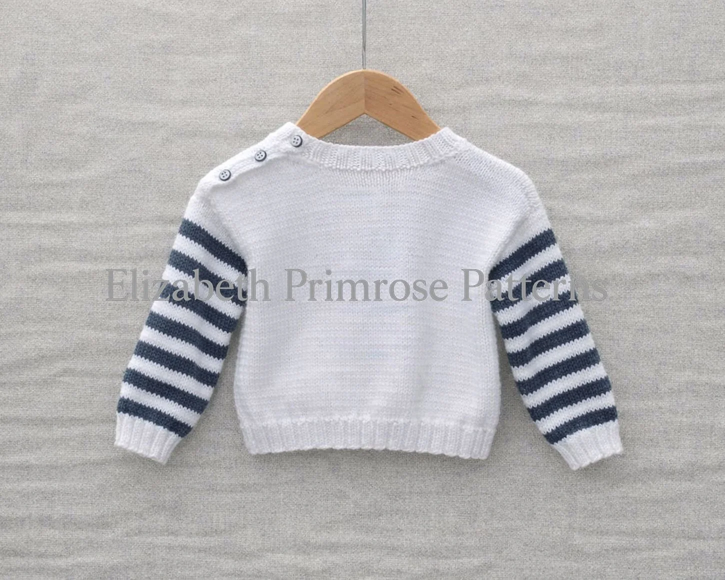 Back view of a white children’s jumper with grey striped sleeves hanging on a wooden hanger against a soft, neutral background.