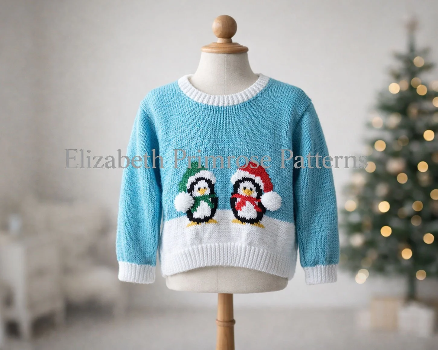 Knitted turquoise jumper featuring two festive penguins in scarves and hats, shown on a child’s mannequin with a warm, softly lit Christmas backdrop.