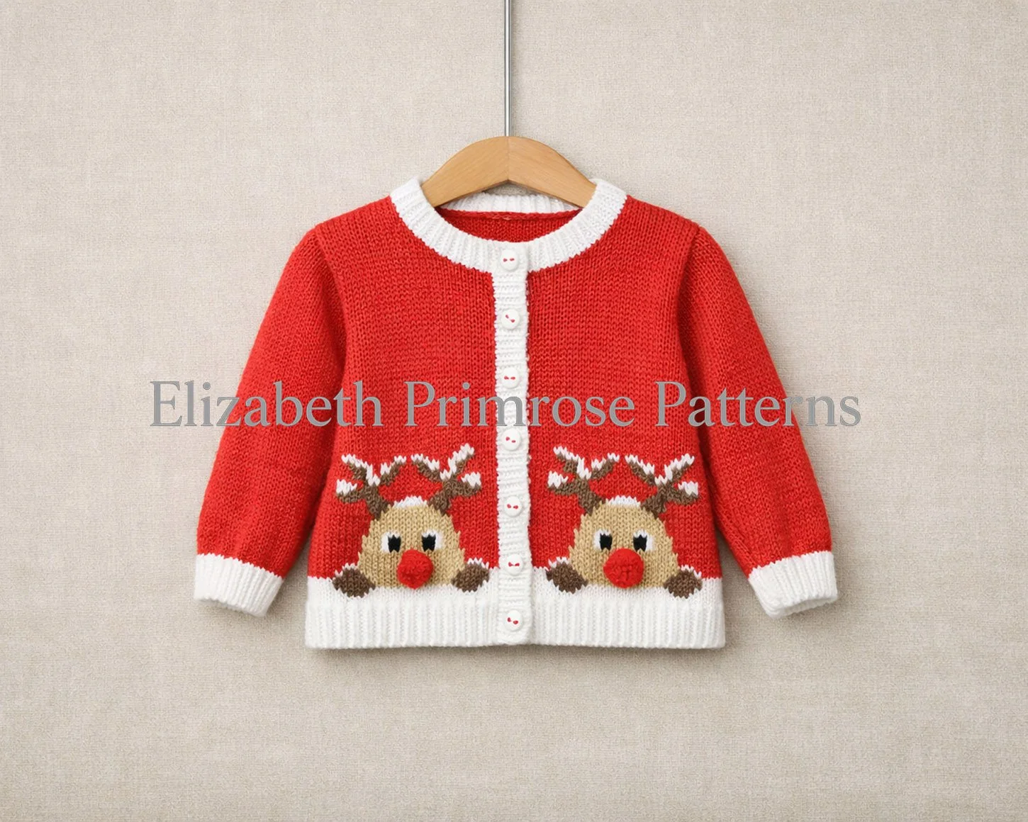 Red children’s round neck cardigan on a wooden hanger with white trims and two Rudolph motifs, shown against a soft beige fabric background.