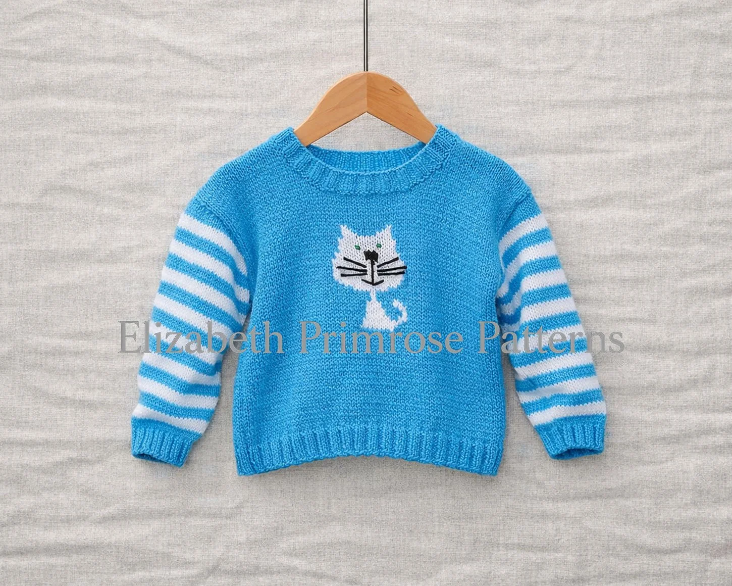 Blue toddler jumper with white cat motif and striped sleeves displayed on a wooden hanger against a soft grey background.